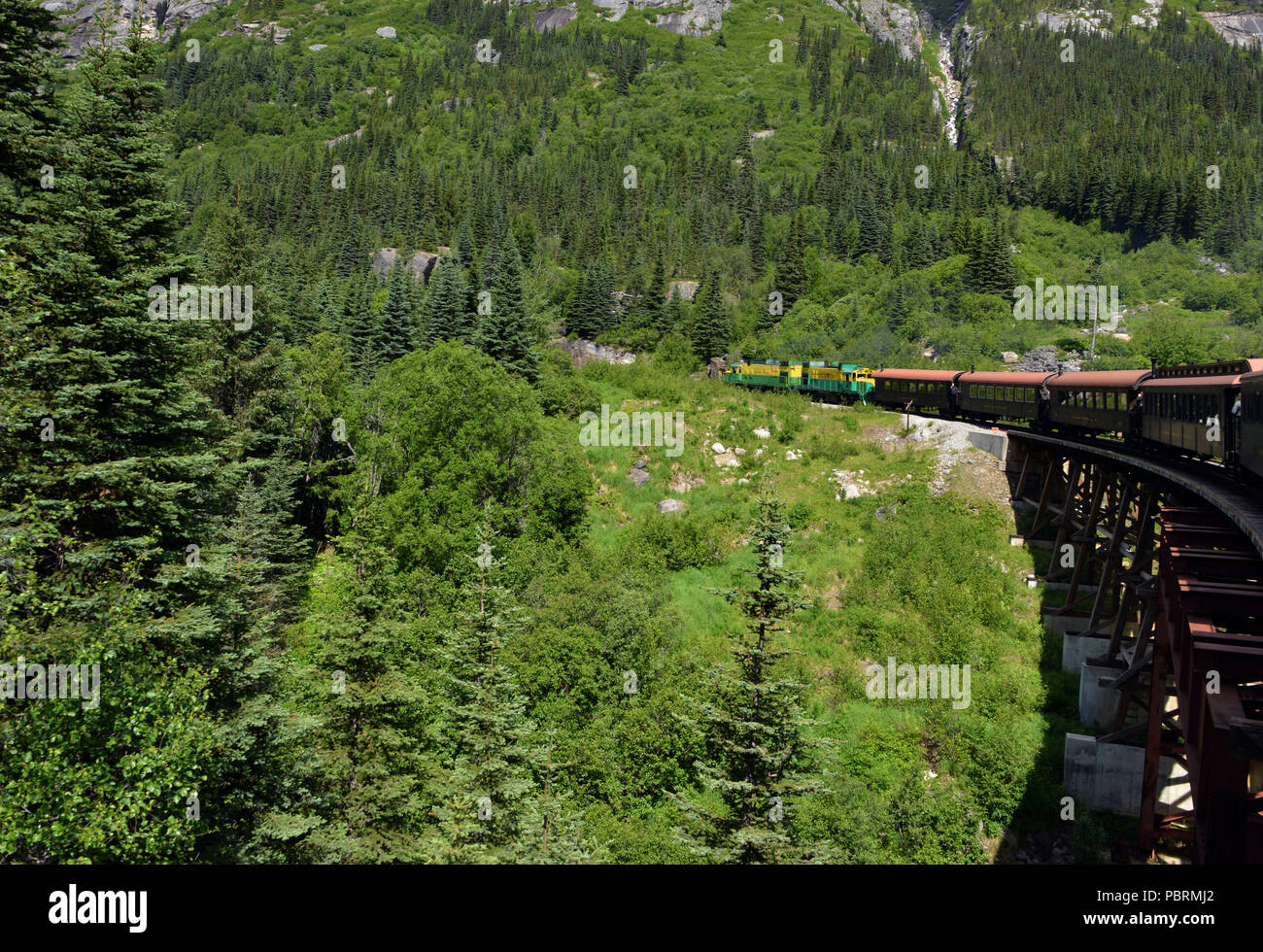 Ein Zug Motor zieht vintage Wagen über einen Bock Brücke auf dem Weg von Skagway, Alaska auf den Gipfel des White Pass - ein 2.885 Fuß Höhe Stockfoto