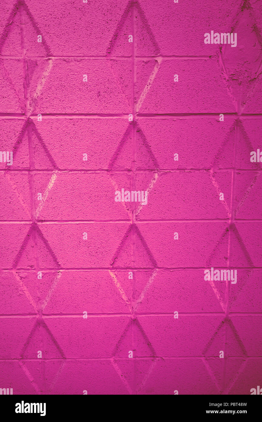 Leuchtend rosa Betonwand mit Rautenmuster. Stockfoto
