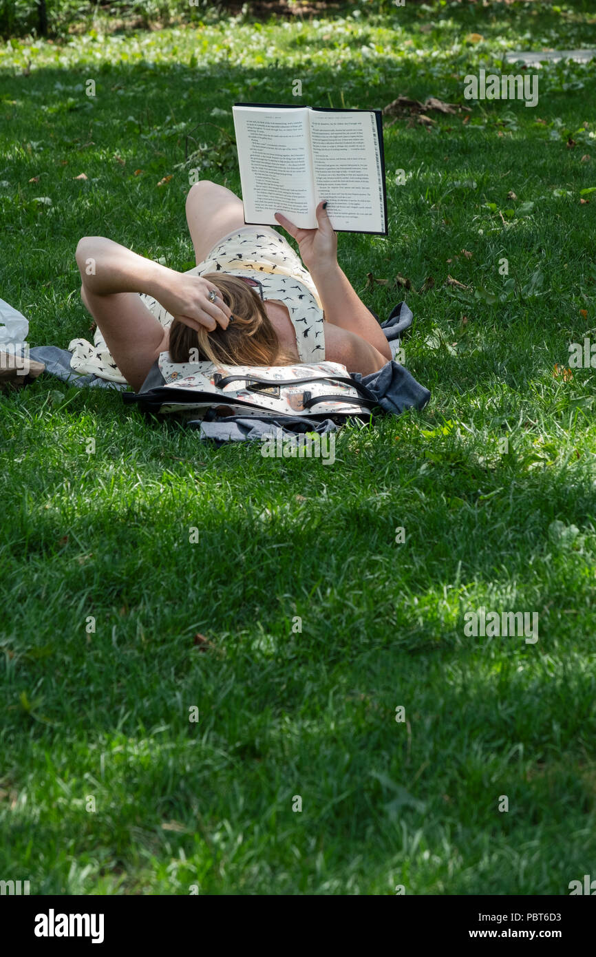 Eine unbekannte junge Dame Roman von Sarah Masse im Schatten im Sommer. Im Washington Square Park in Manhattan, New York City. Stockfoto