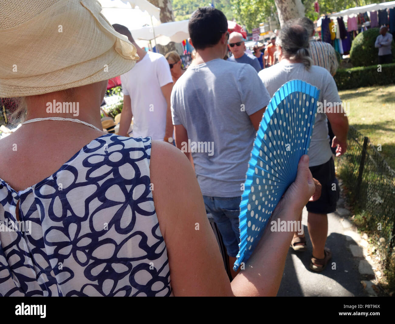 Frau auffächern, selbst mit einem blauen folding Fan wie Sie geht um ein Markt im Süden Frankreichs Stockfoto