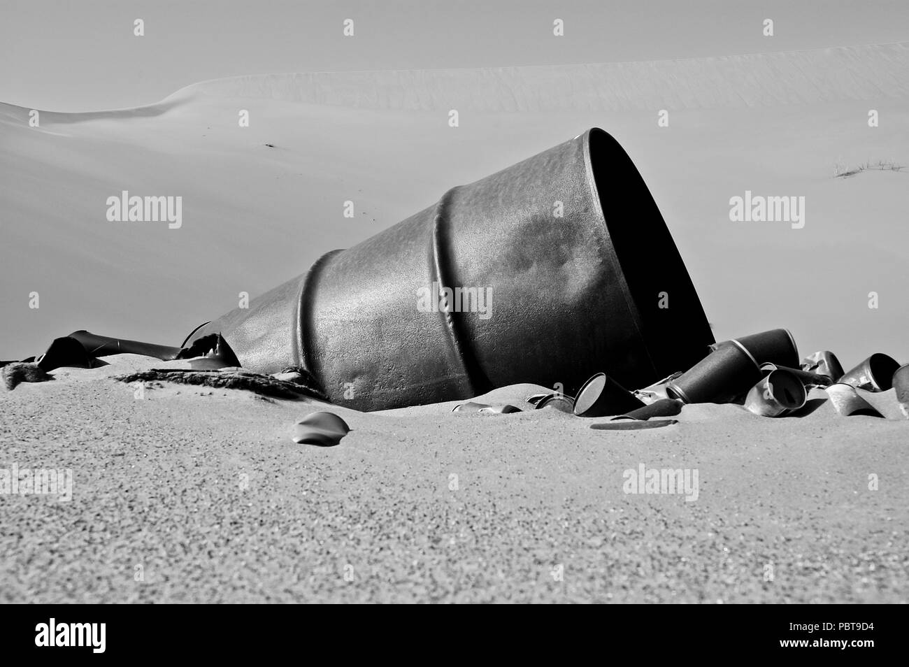 Rostige Dosen und Zylinder auf dem Sand in der Wüste. Stockfoto