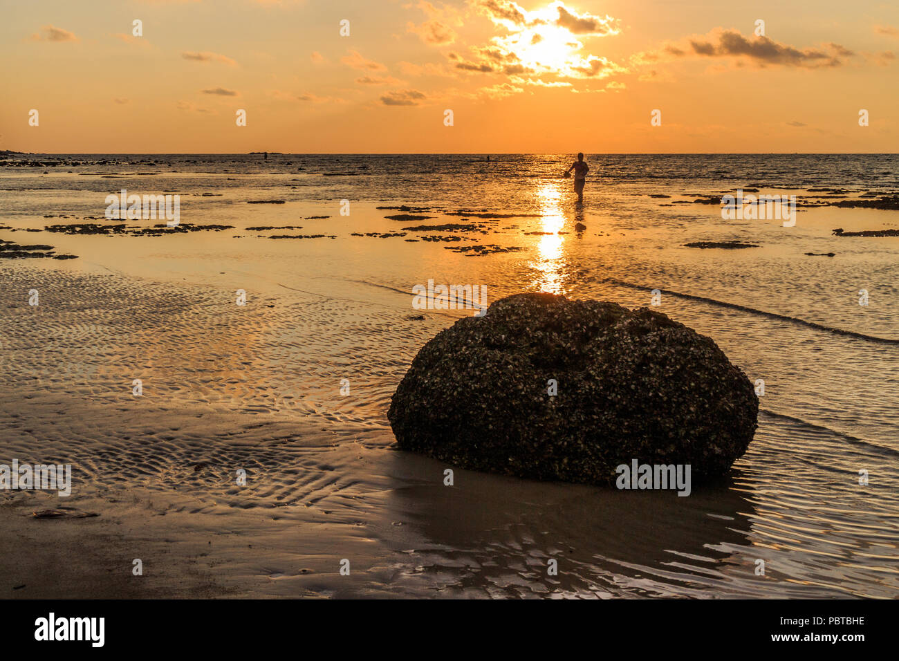 Rock und Fisherman Silhouette bei Sonnenuntergang, Kamala Beach, Phuket, Thailand Stockfoto