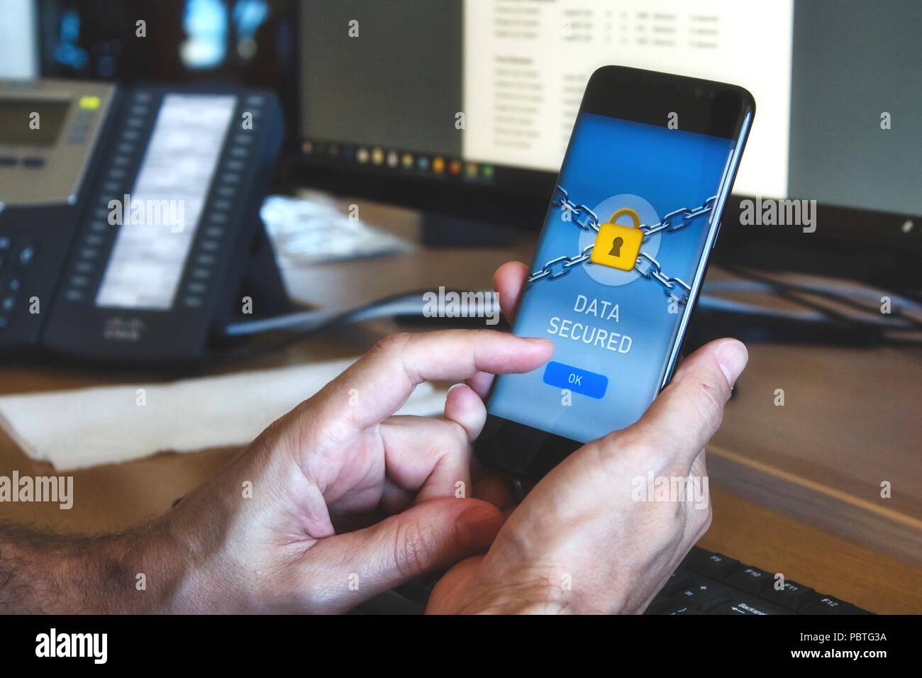 Mann mit einem mobilen Smart Phone mit einer Datensicherheit Anwendung mit einem gelben Vorhängeschloss und drücken auf die Taste "OK" mit Finger Stockfoto