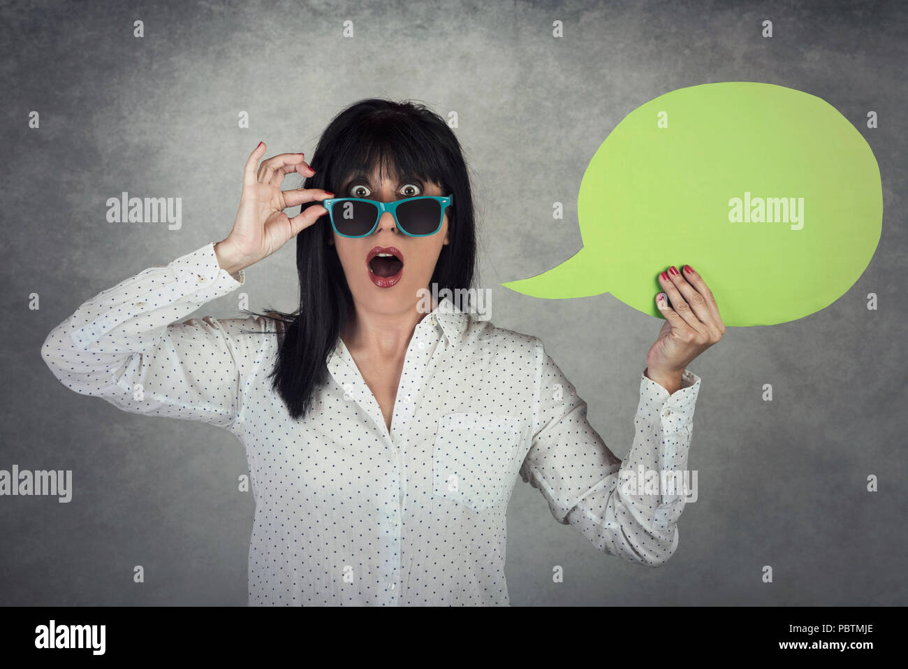 Junge Frau mit einer Sprechblase auf grauem Hintergrund Stockfoto