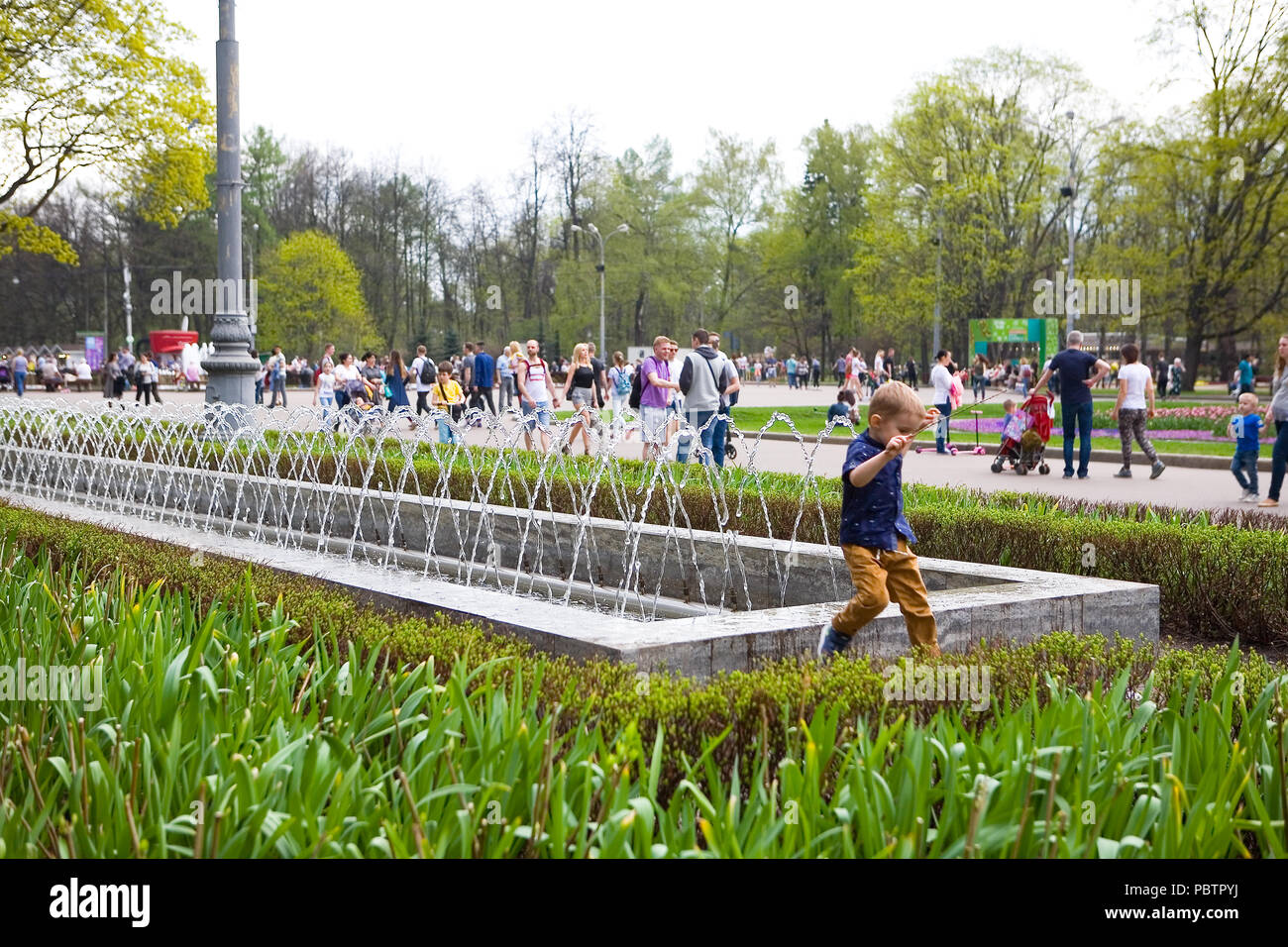Moskau, Russland, 2. Mai 2018: Ein kleiner Junge springt neben einem Brunnen im Sokolniki Park. Stockfoto