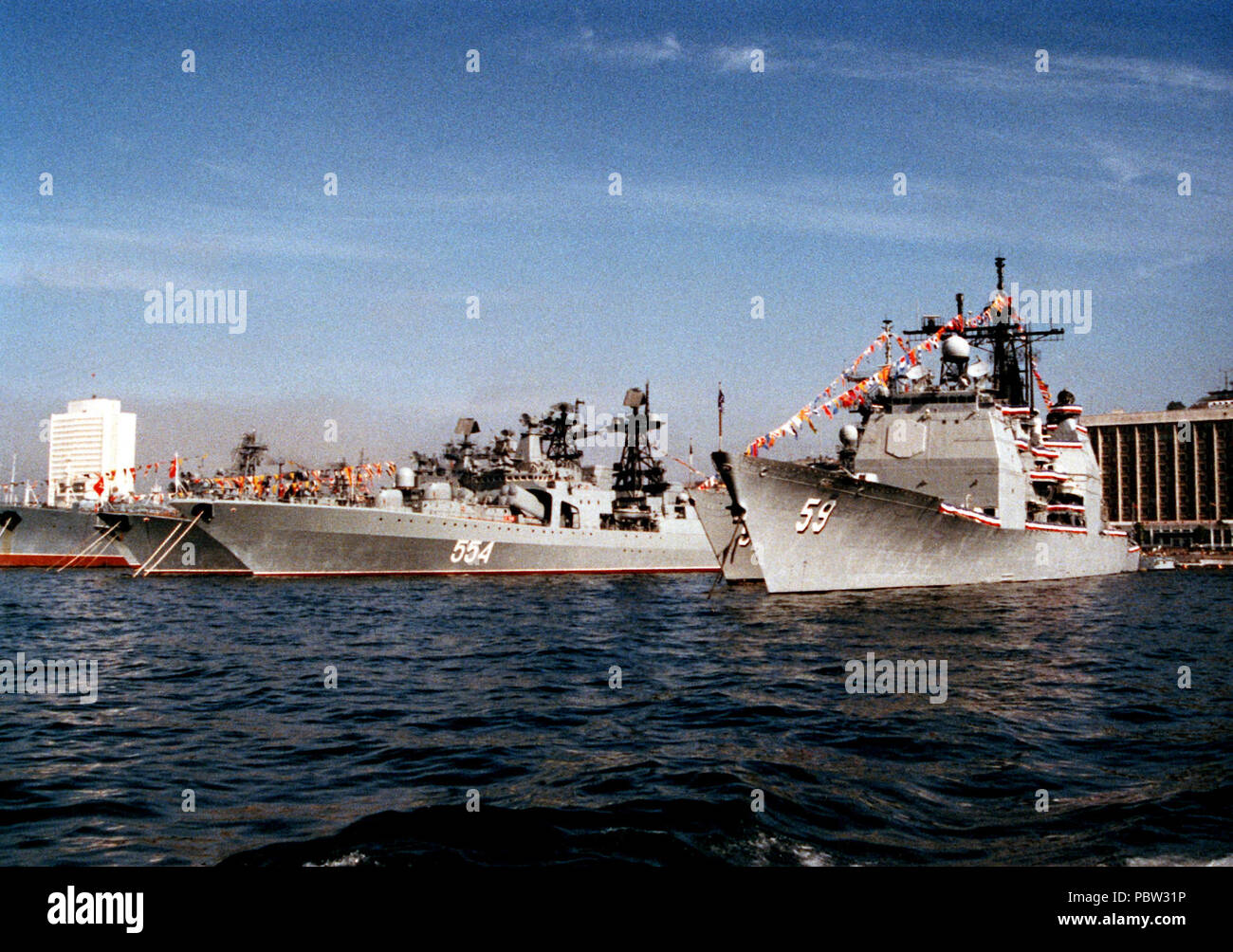 ReubenJames AdmiralVinogradov & Prinseton & 1990. Die Lenkwaffen-kreuzer USS Princeton (CG-59), rechts, liegt gefesselt in der Nähe von mehrere Schiffe der Sowjetischen Pazifikflotte. Das sowjetische Schiff Dritter von links ist der Udaloy Klasse Lenkwaffen-zerstörer ADMIRAL WINOGRADOW. Die Princeton und die lenkwaffenfregatte USS Reuben James (FFG-57), die sich auf dem Princeton Steuerbord gebunden ist, sind in der Stadt für einen Geschäfts- oder Firmenwert zu besuchen. Stockfoto