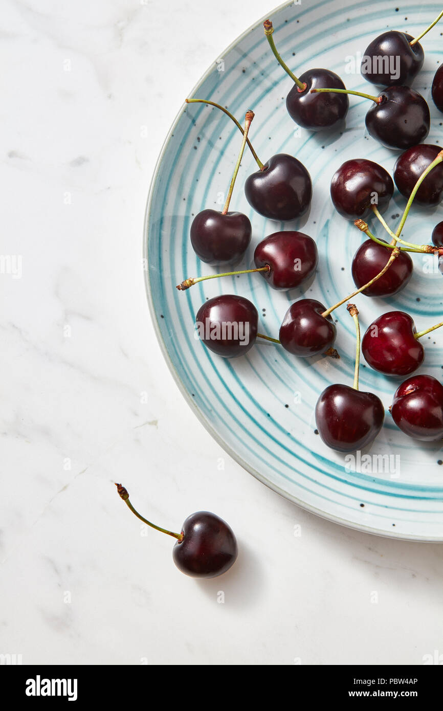 Süße Beeren rot reif auf blauen Platte auf grauem Hintergrund mit Platz für Text. Flach. Stockfoto