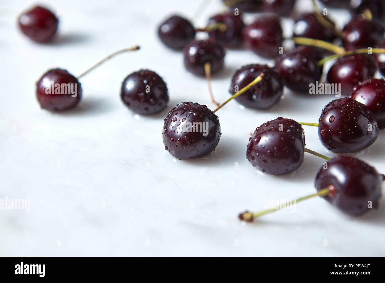 Rote Kirschen in Wassertropfen auf einem Marmor Hintergrund mit kopieren. Stockfoto