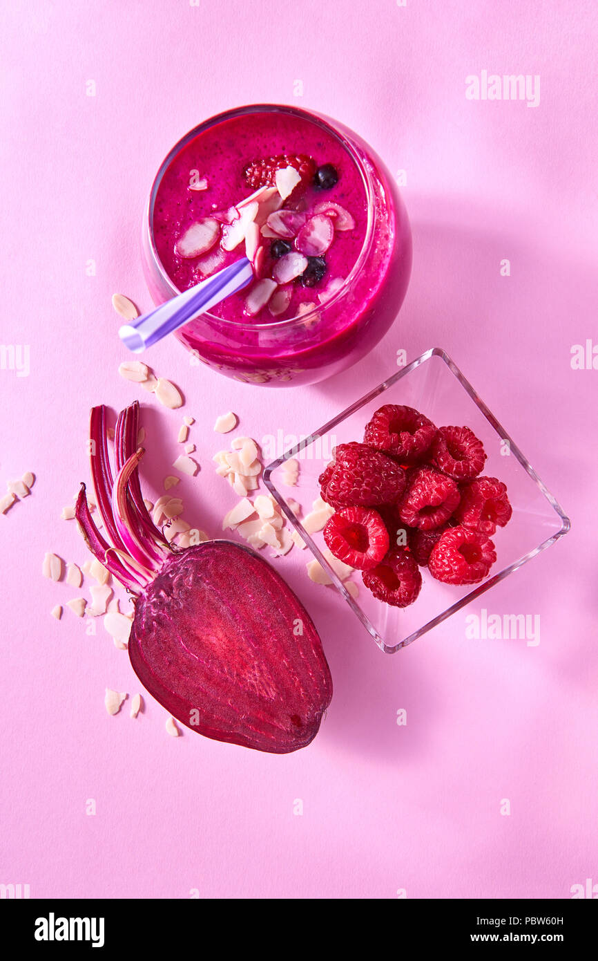 Frische saftige detox Smoothies im Glas Schale mit roten Beeren, Rote Beete, Mandeln auf einem rosa Papier Hintergrund. Ansicht von oben. Stockfoto