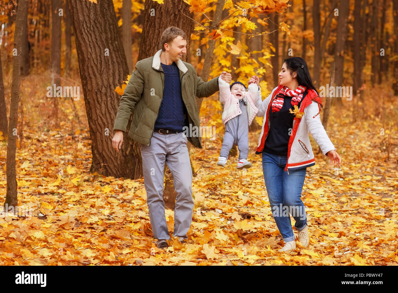 Junge Eltern gehen und spielen mit kleinen Tochter im Herbst Park. Papa und Mama mit Baby. Happy Family Konzept Stockfoto