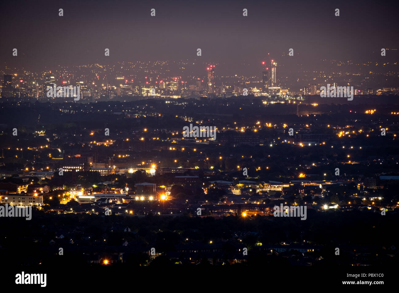 Nacht Blick von der Stadt Manchester, UK unten und aus der Ferne mit einem weiten Blick über die Lichter von Winter Hill, Bolton genommen Stockfoto