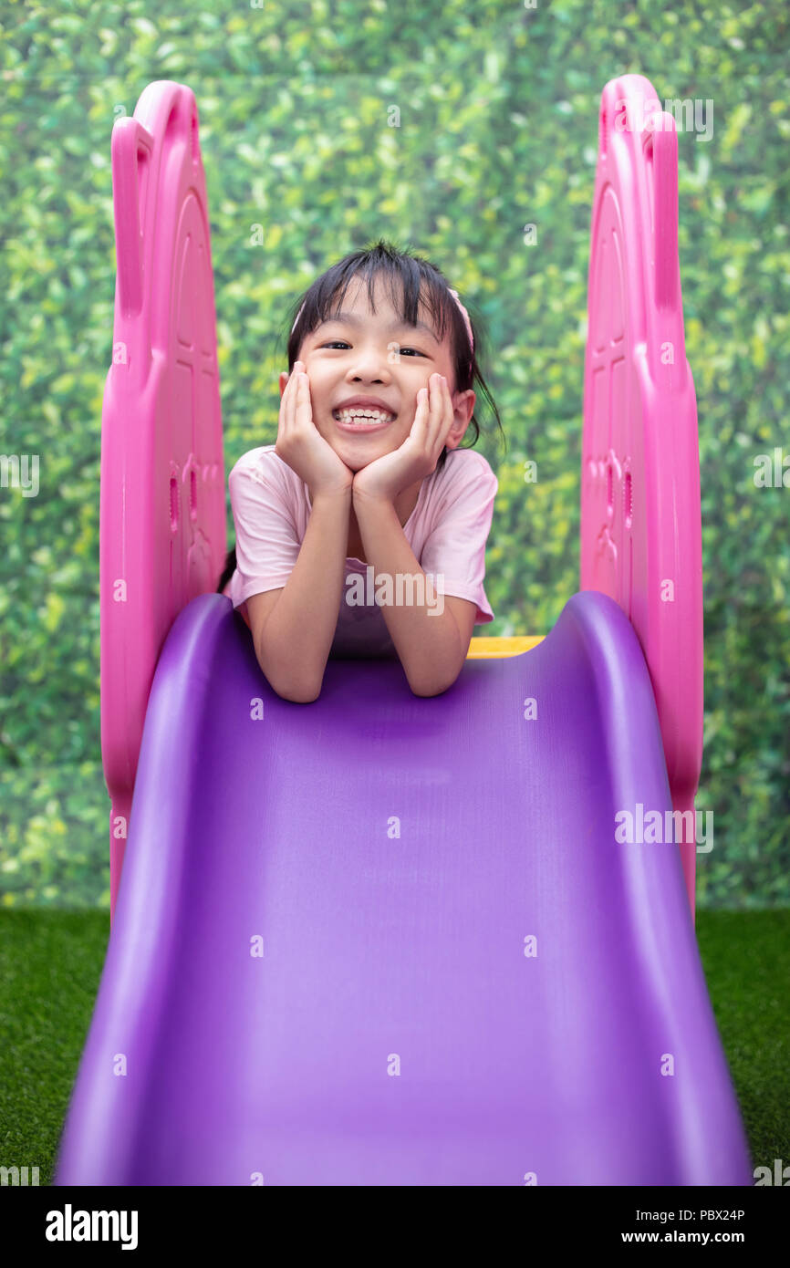 Asiatische chinesische Mädchen spielen auf der Folie am Spielplatz im Freien Stockfoto