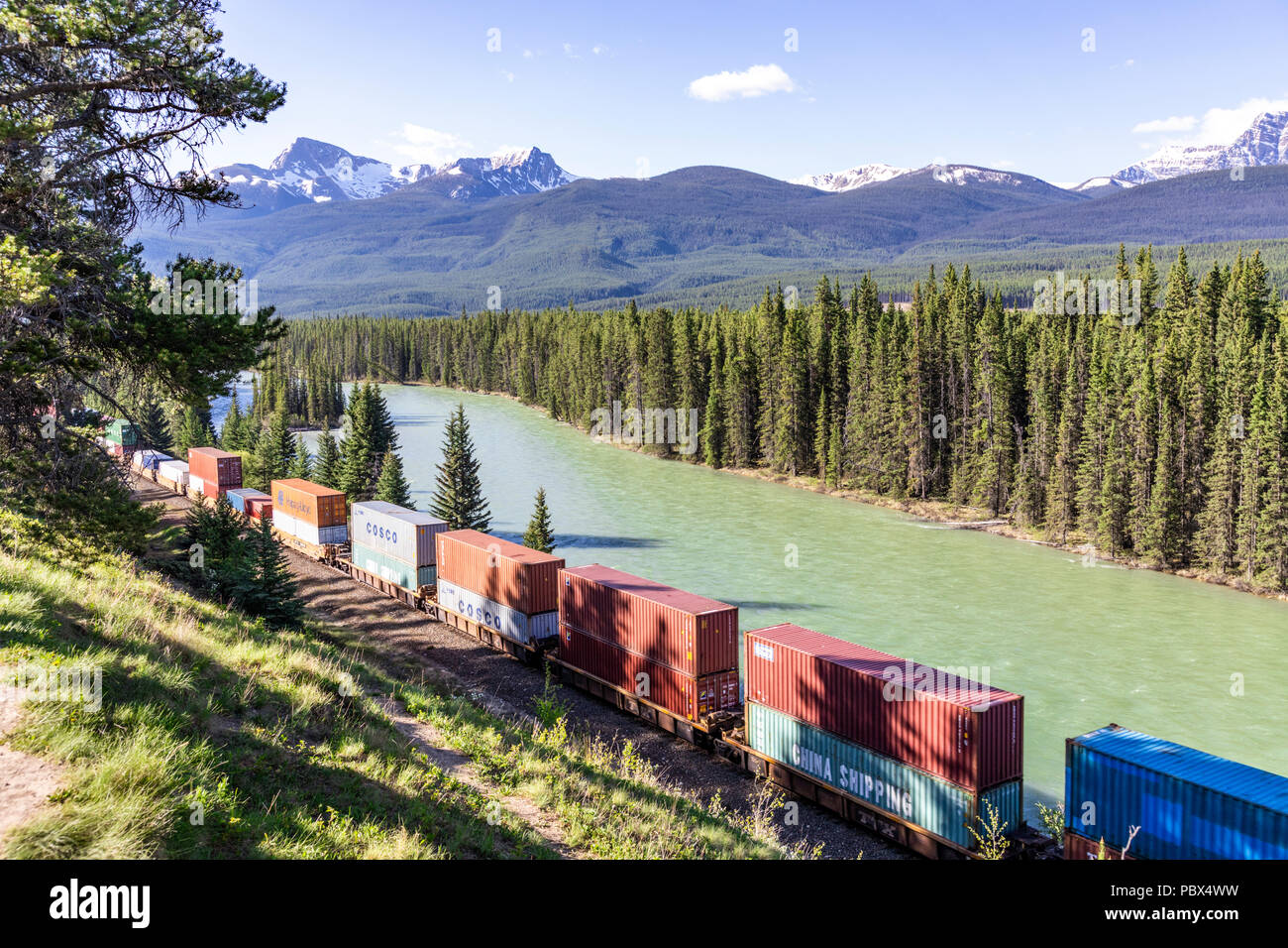 Ein Güterzug auf der Canadian Pacific Railway neben dem Bow River und Rocky Mountains auf Schloss Ausfahrt NW von Banff, Alberta, Kanada läuft Stockfoto