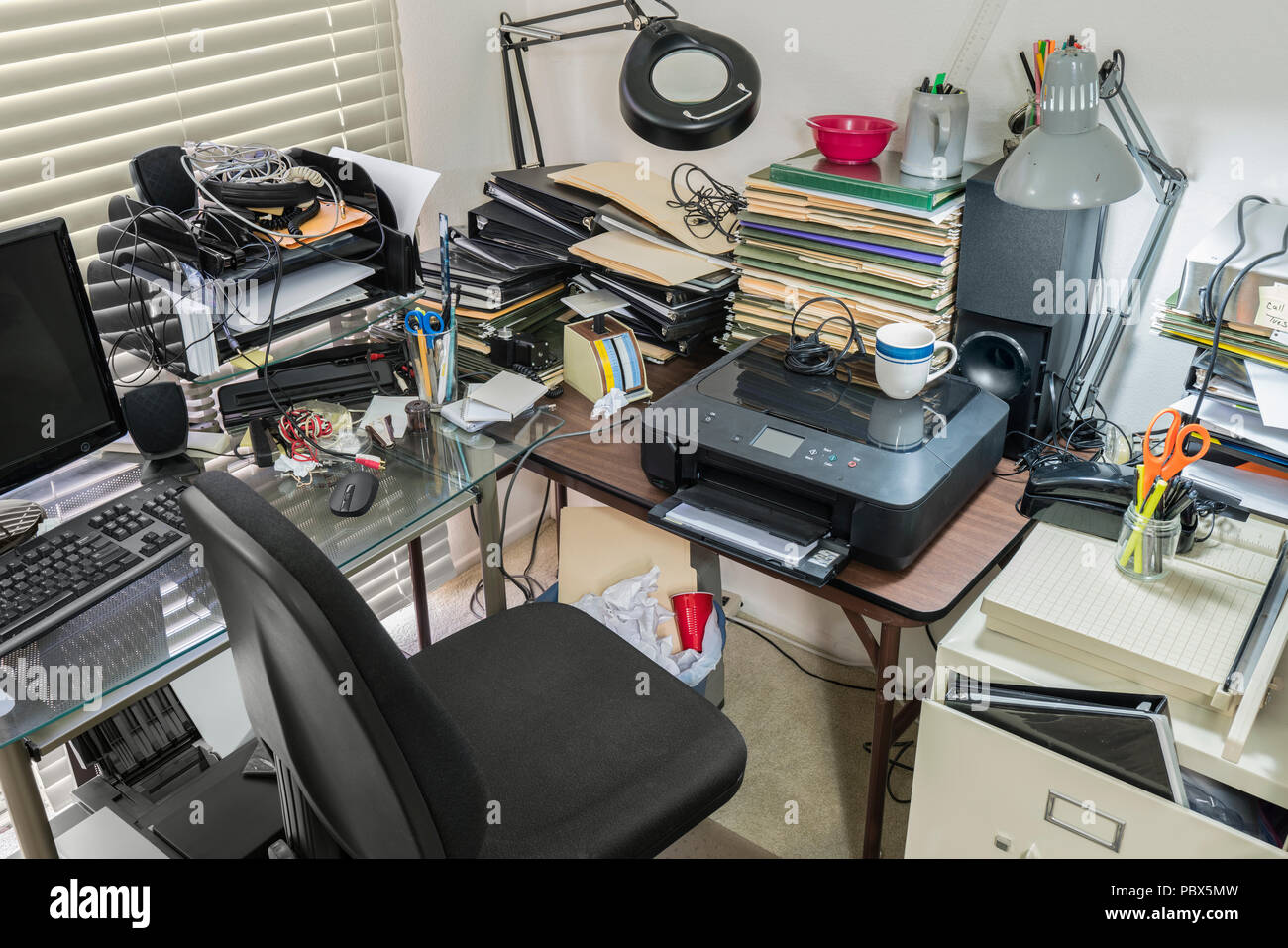 Unordentliches Büro Schreibtisch und Tisch mit Stapeln von Dateien und ungeordnet durcheinander. Stockfoto