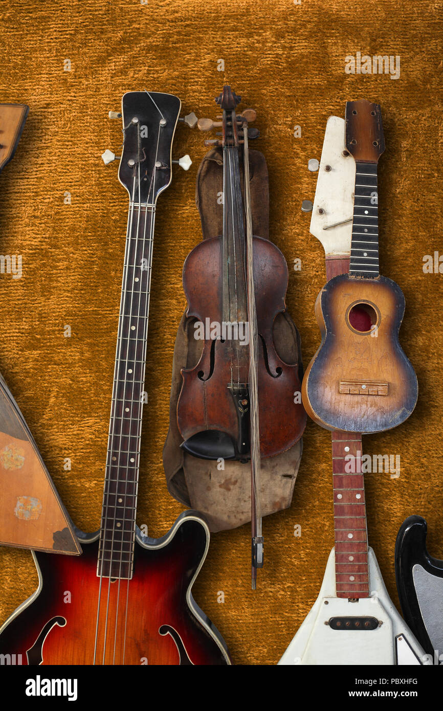 Musikinstrument - Vintage Bass Gitarre, Violine, balalaika auf einem braunen Plüsch Hintergrund. Stockfoto