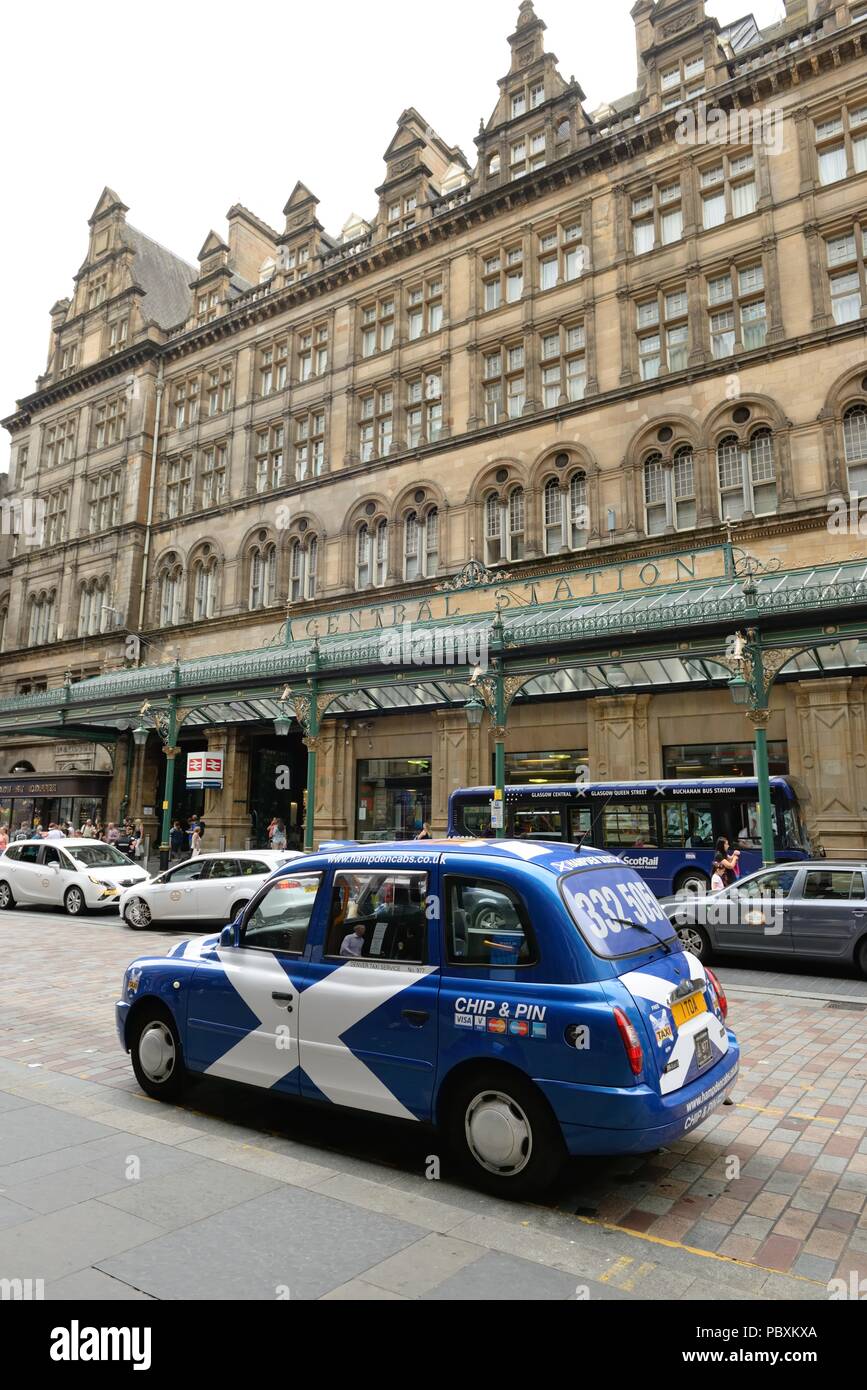 Die blauen und weißen saltire Fahne ziert ein Taxi am Haupteingang Hauptbahnhof von Glasgow in Schottland, Großbritannien und das Central Hotel. Stockfoto