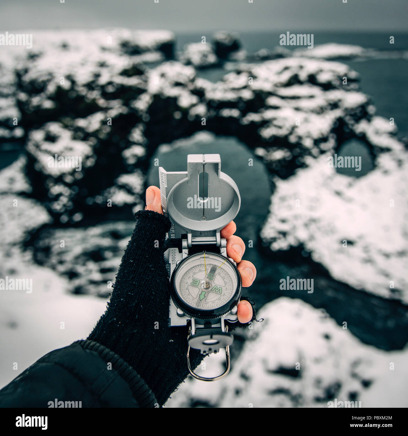 Männliche Hand, Sicht, mit einem Kompass in einer verschneiten Winterlandschaft an Gatklettur Arch Rock, Island, Europa Stockfoto