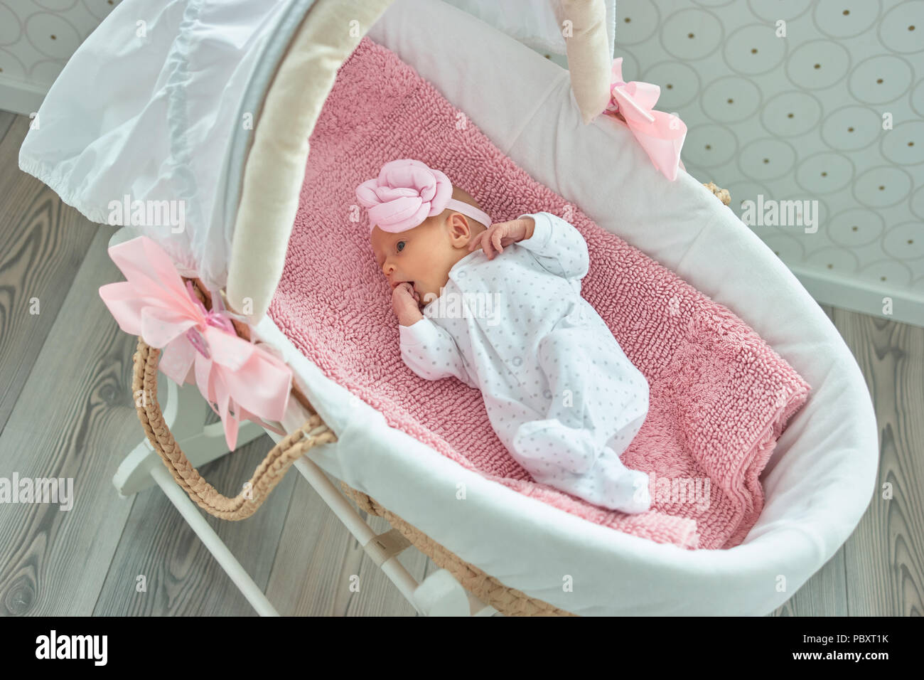 Neugeborene Mädchen mit hand Süß im Mund. Schlaflied Moses Korb. Stockfoto