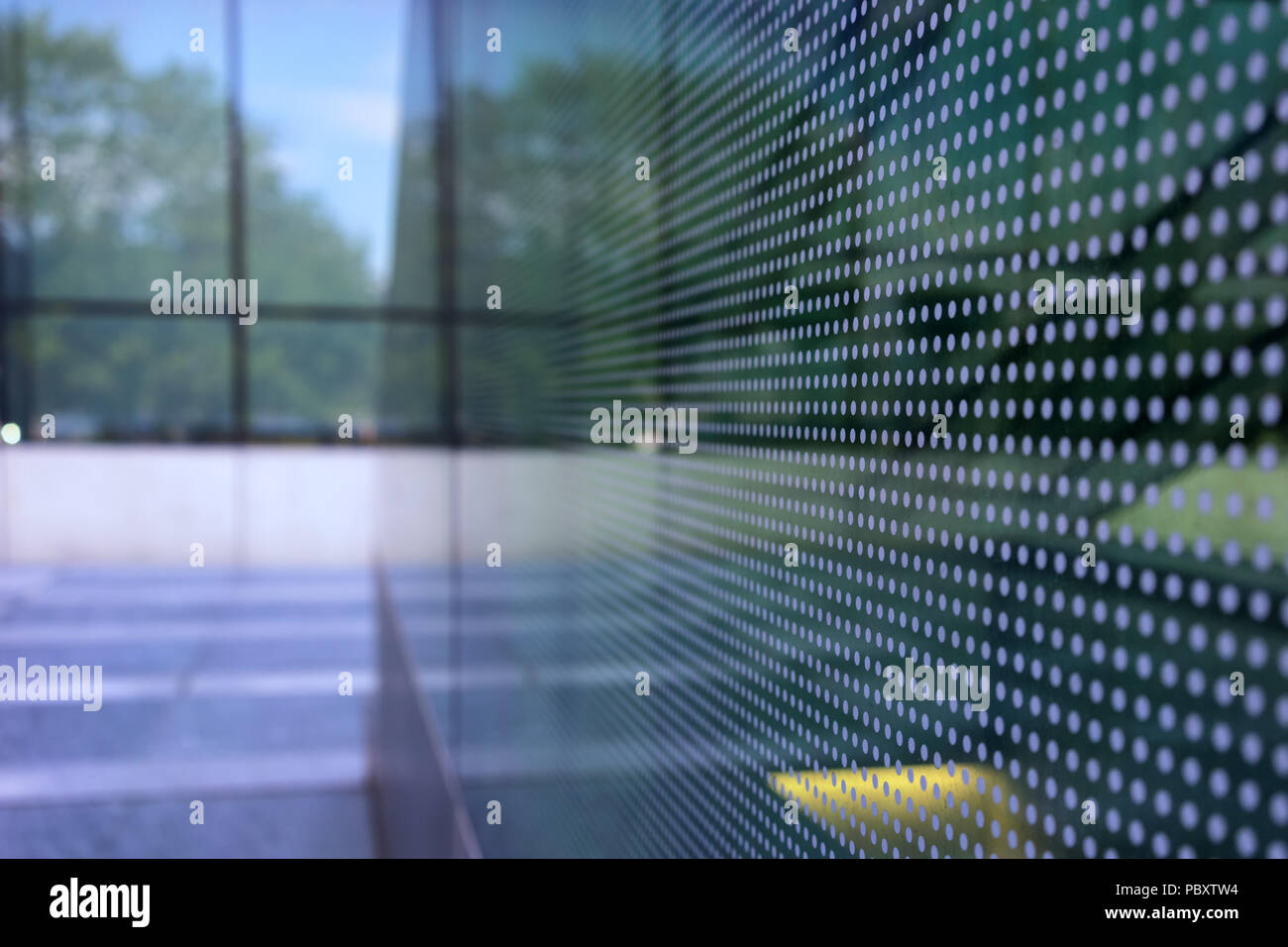 Park Reflexion in den Fenstern der Fassade eines modernen Gebäudes, mit Punkten als Hintergrund Stockfoto
