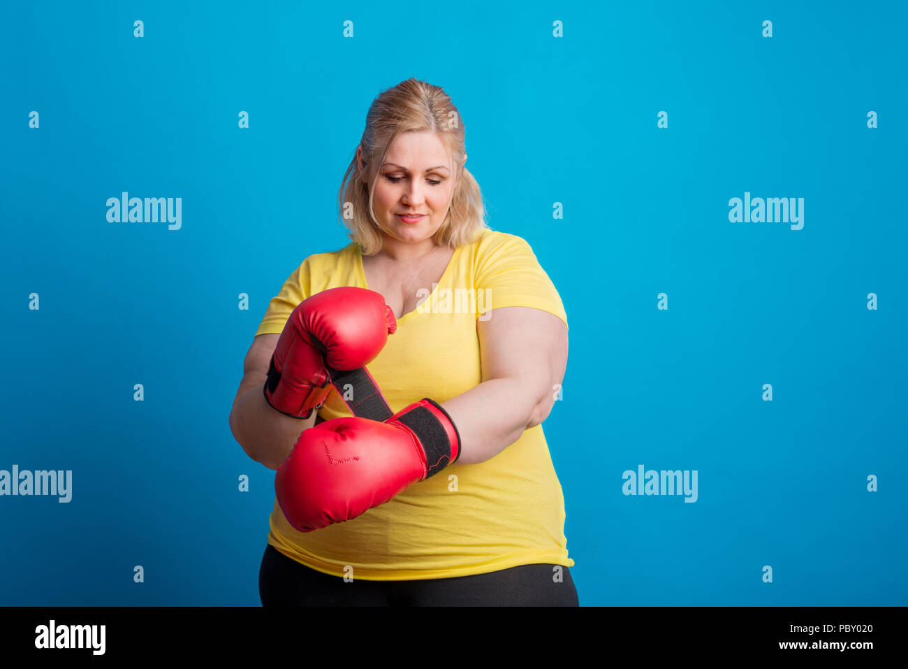 Portrait Of Happy übergewichtige Frau auf Boxhandschuhe im Studio. Stockfoto