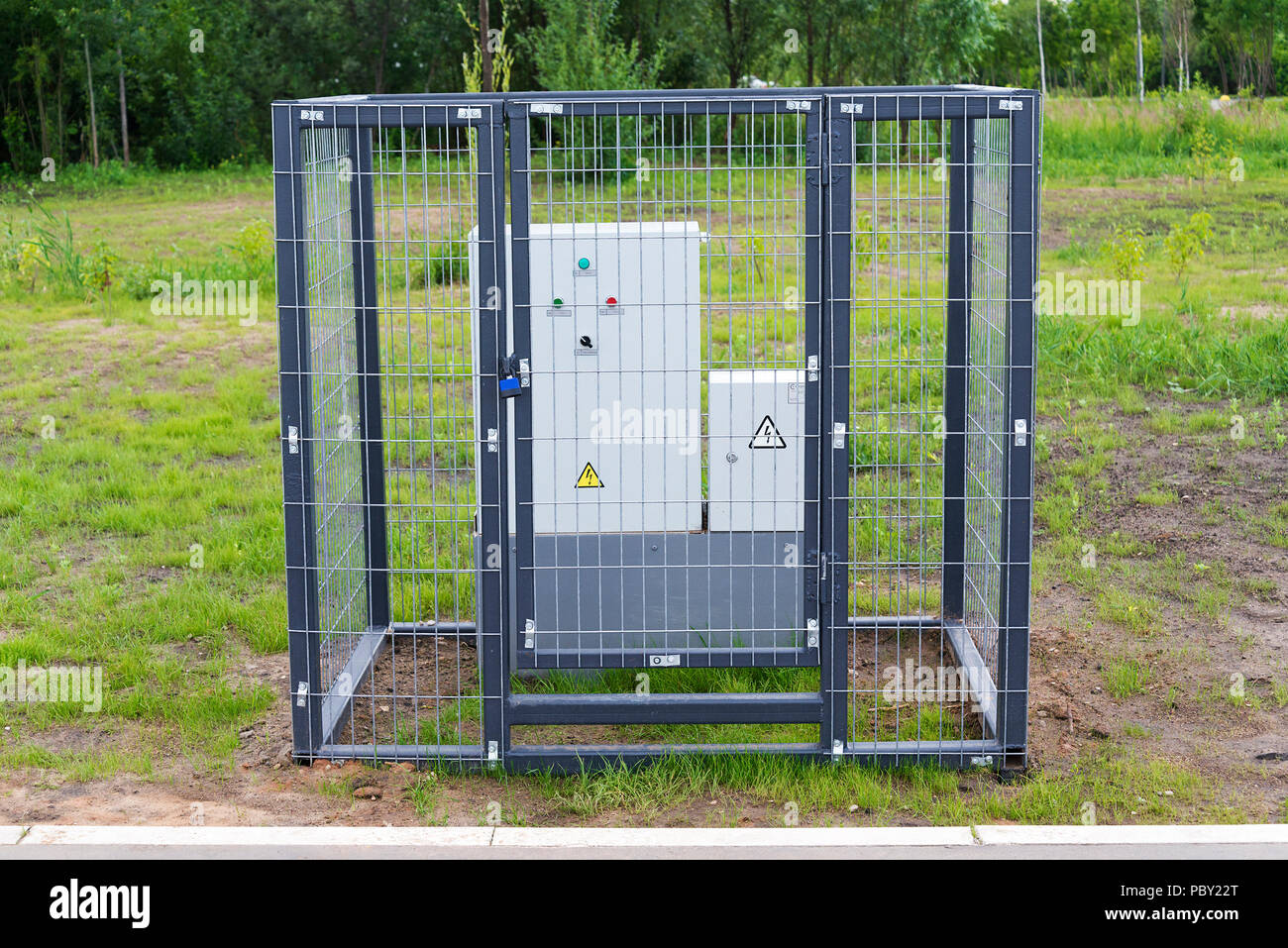 Ein kleiner Trafo hinter einem Metallgitter in einem Stadtpark. Stockfoto