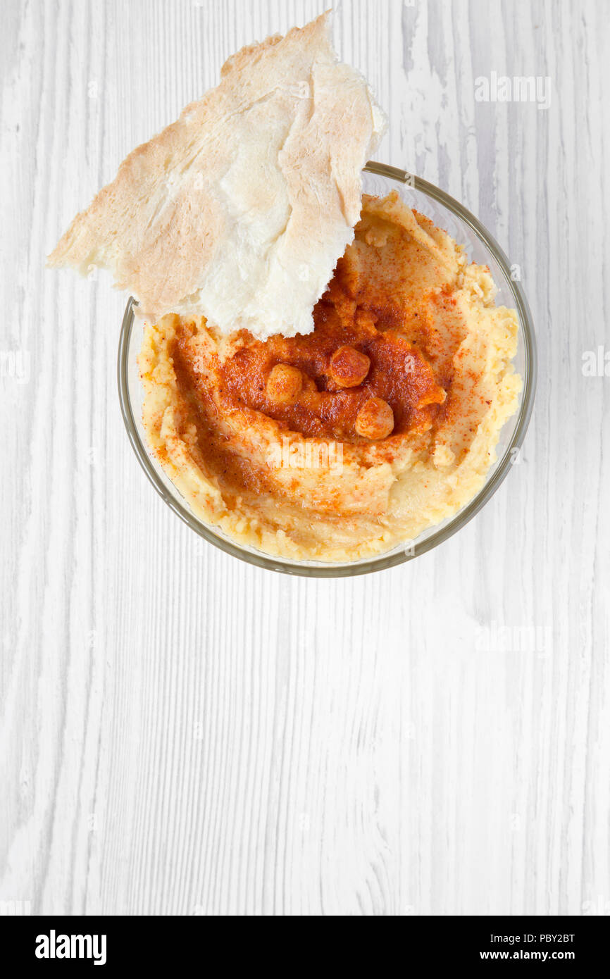 Volle Schüssel von Hummus mit gerösteten Kichererbsen, Paprika, Olivenöl und pita Brot auf einem weißen Holz- Oberfläche. Flach. Stockfoto