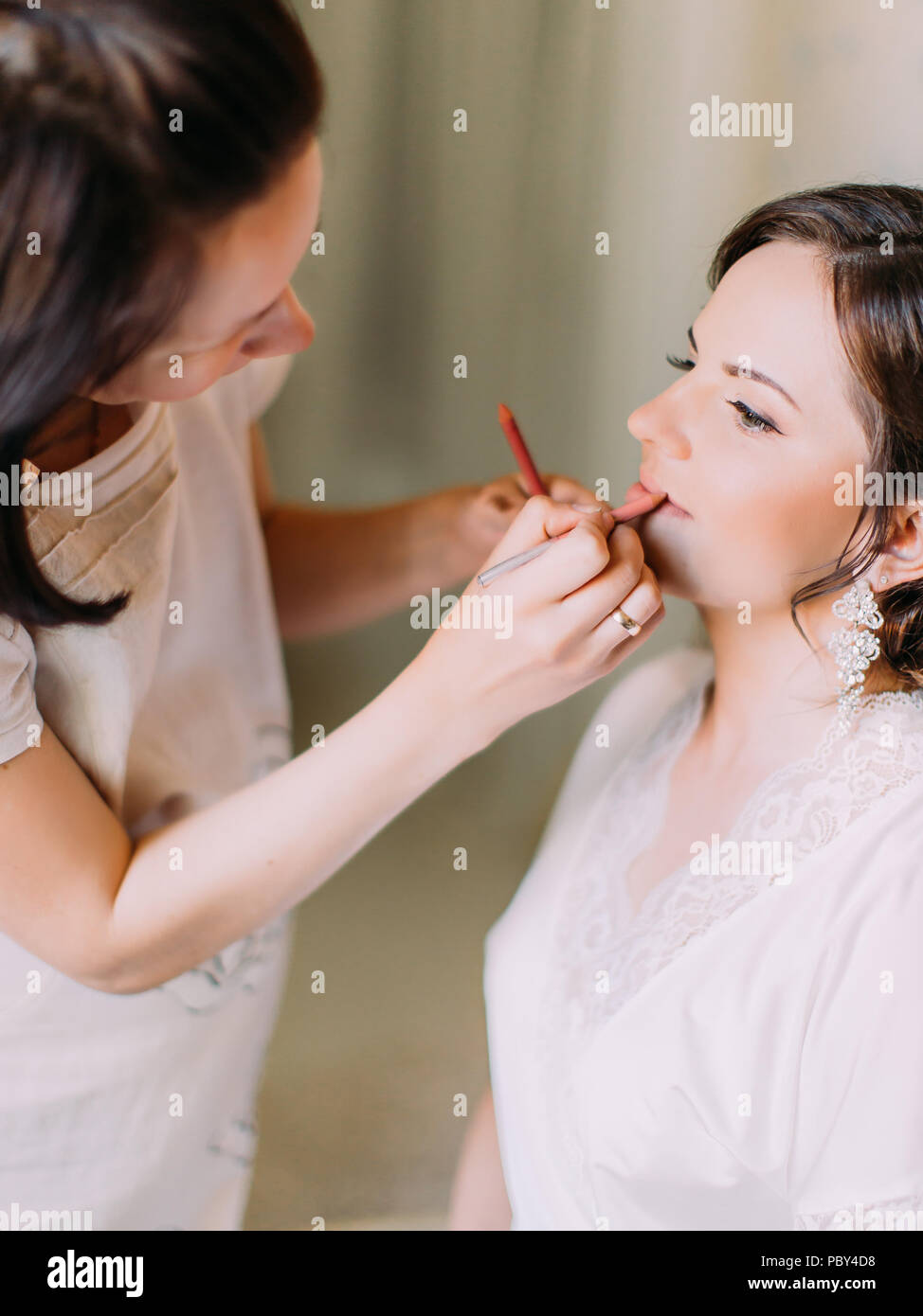Die vertikale Ansicht des womanmakeup Künstler tun das Make-up für die Braut Stockfoto