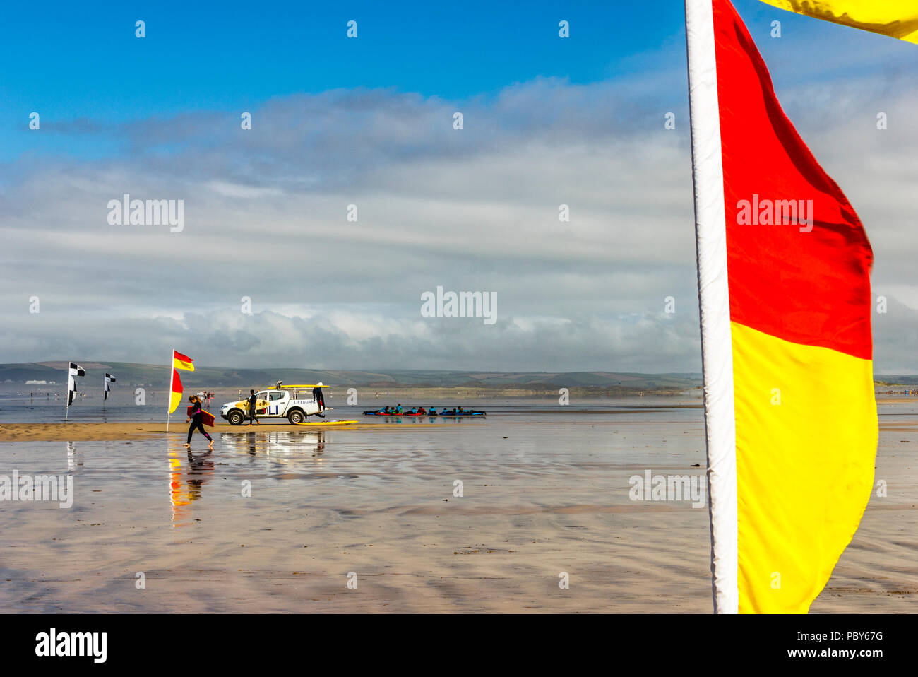 Surfer und Sicherheit markierungsfähnchen am Strand von Westward Ho!, Devon, Großbritannien Stockfoto