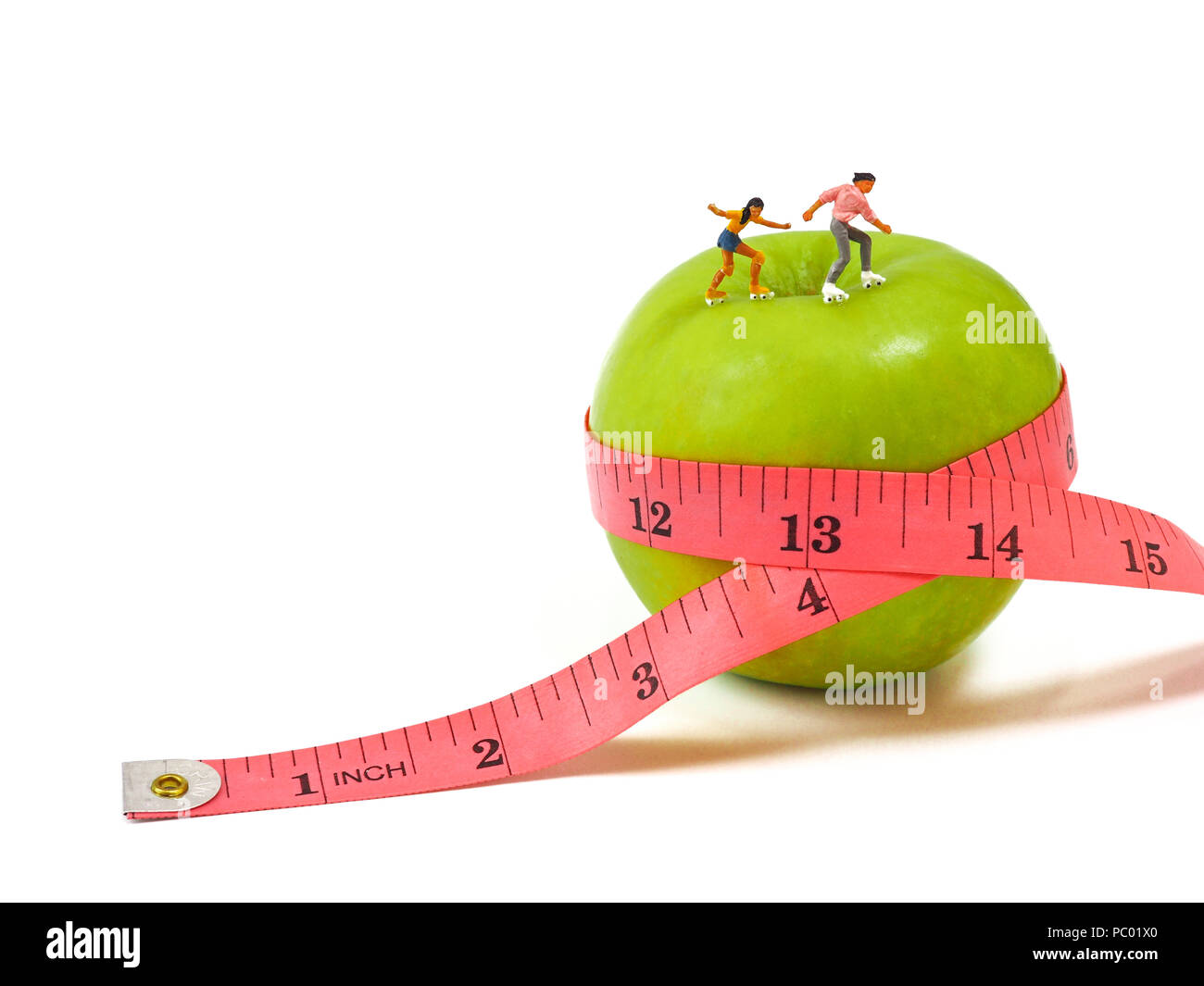 Miniatur Frau Schlittschuhlaufen auf grünem Apfel und Maßband, das Denken von Gewichtsverlust und schlanken Körper. Gesunder Lebensstil Konzept. Stockfoto