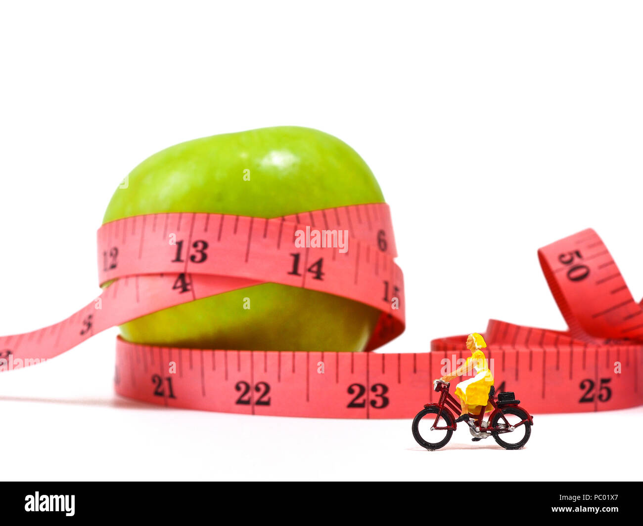 Miniatur Frau reiten Fahrradverleih in der Nähe von Green Apple und Maßband, das Denken von Gewichtsverlust und schlanken Körper. Gesunder Lebensstil Konzept. Stockfoto