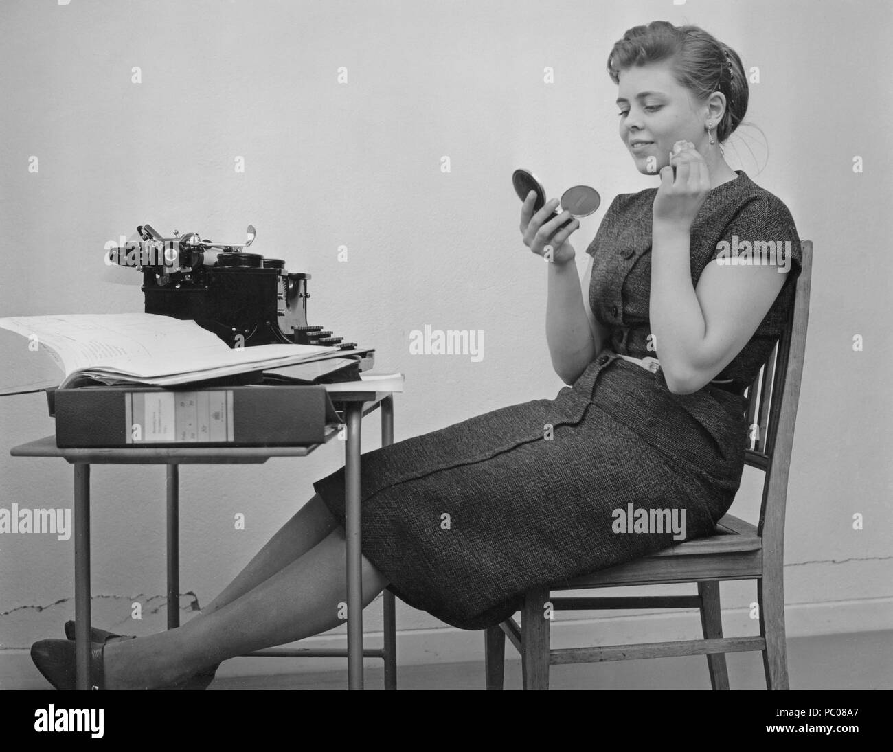 Office girl in den 1950er Jahren. Ein junges Mädchen an ihrer Schreibmaschine ist eine Pause von der Arbeit und verbessern Ihr Make-up. Schweden 1955 Stockfoto