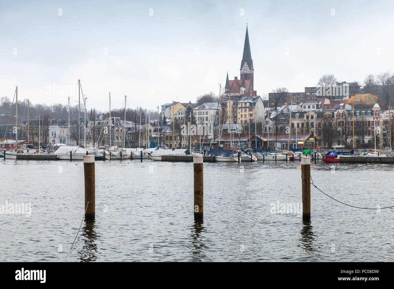 Flensburg Stadt im Winter, Deutschland. Küsten Skyline mit hölzernen Anlegestellen Spalten in Wasser Stockfoto