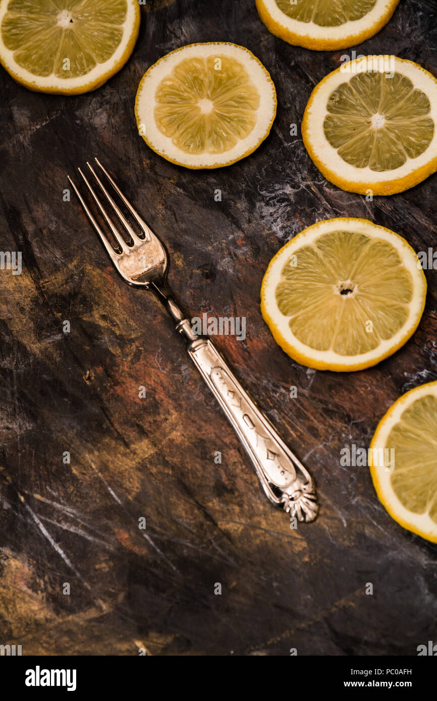 Frisch geschnittene reife Zitronen und Gabel auf Schwarz Stockfoto
