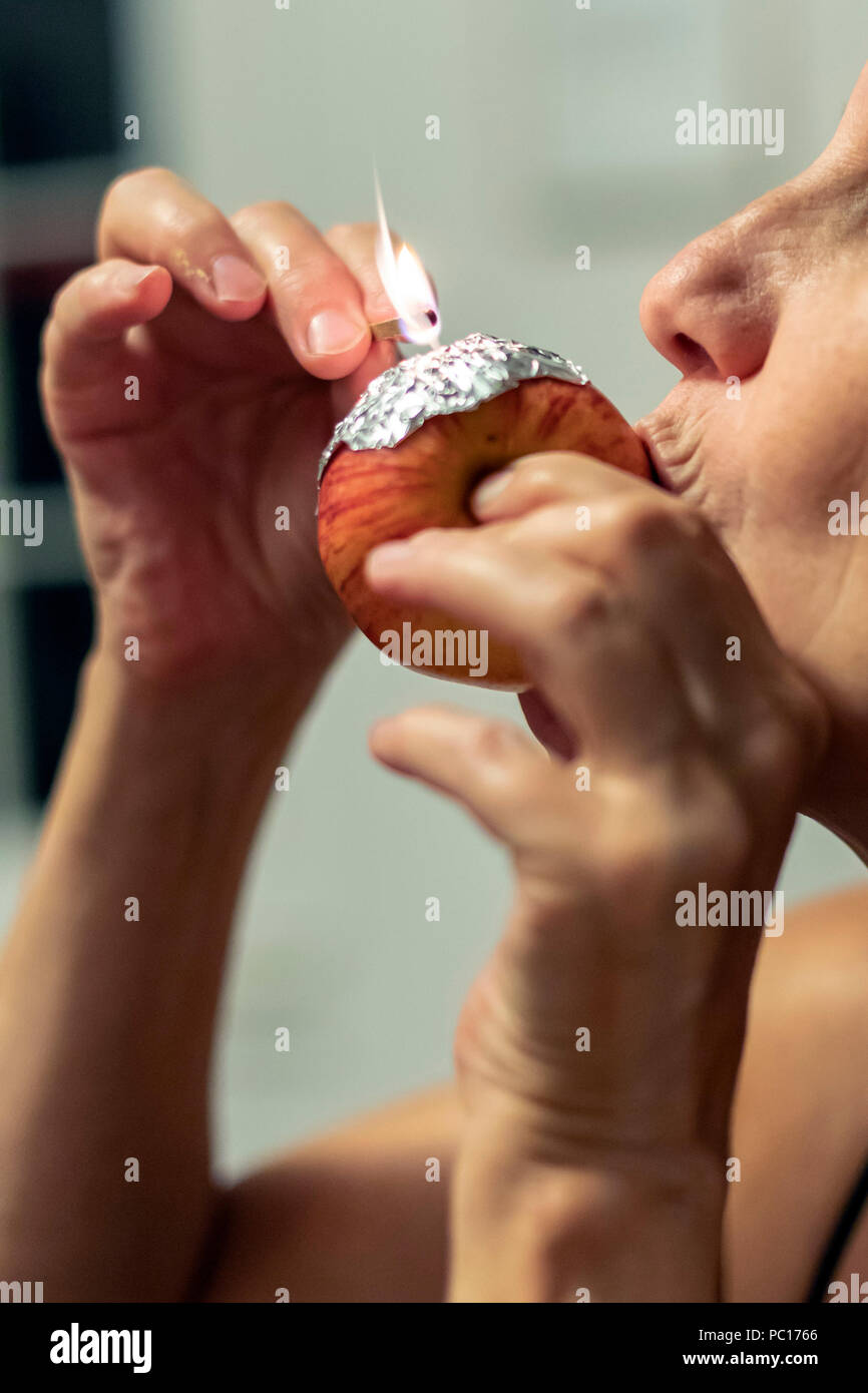 Eine Frau, die Marihuana raucht, ein Apple als ein Rohr. Stockfoto