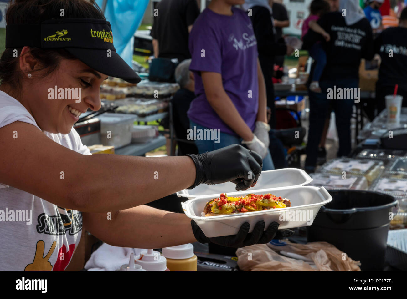 Dearborn, Michigan - eine Frau fügt Toppings zu einem Halal heißer Hund am Smileys Halal Fleisch stand auf einer muslimischen politische Kundgebung. Halal Fleisch wird in bereit Stockfoto
