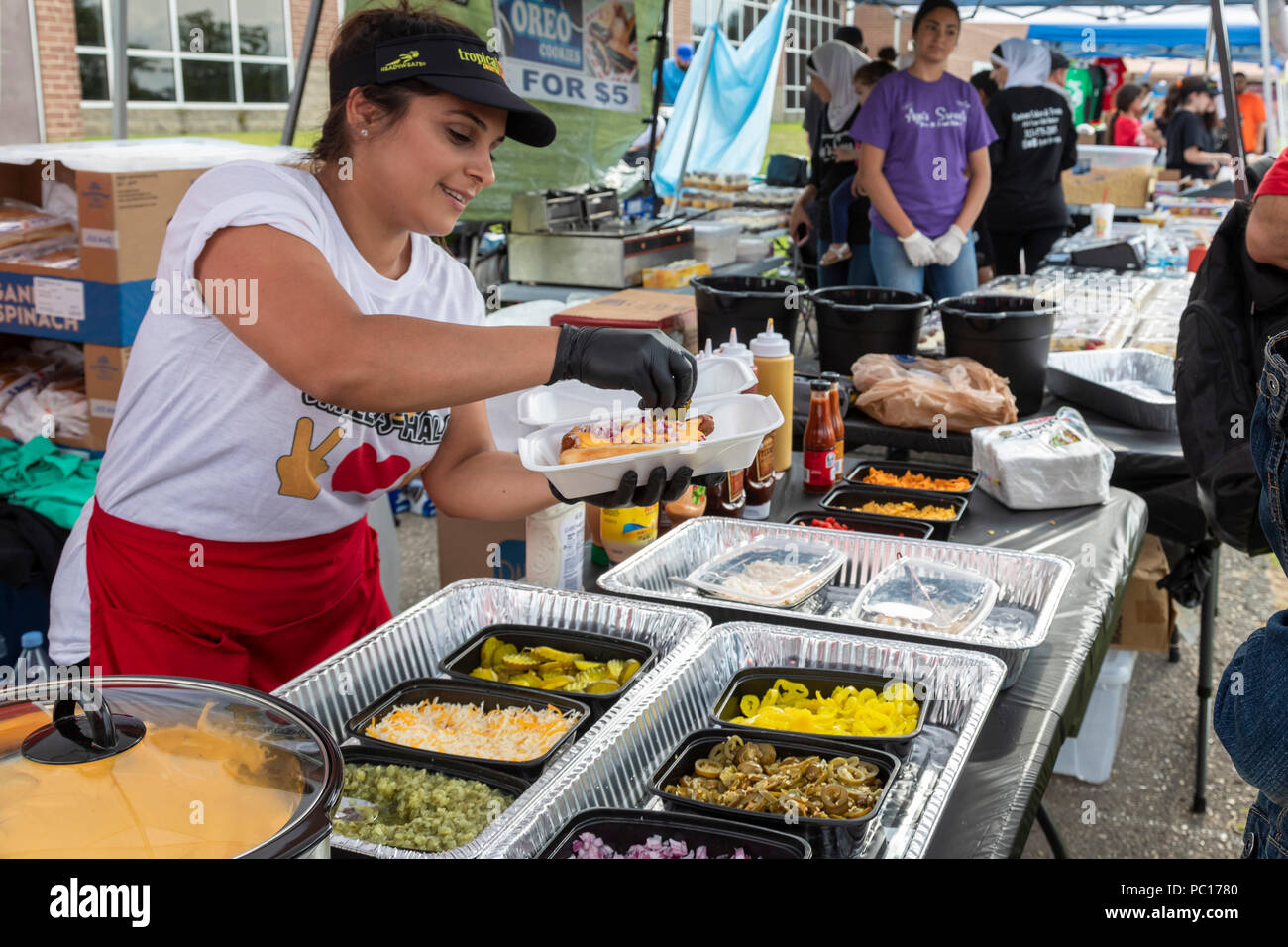 Dearborn, Michigan - eine Frau fügt Toppings zu einem Halal heißer Hund am Smileys Halal Fleisch stand auf einer muslimischen politische Kundgebung. Halal Fleisch wird in bereit Stockfoto