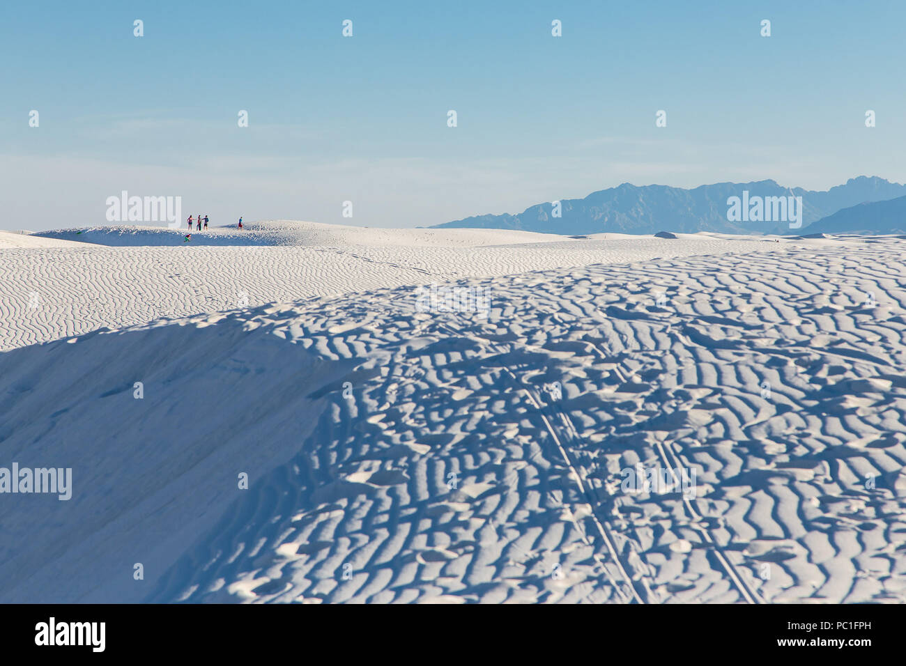 Die Menschen in die Ferne wandern unter den großen weißen Sanddünen. Stockfoto