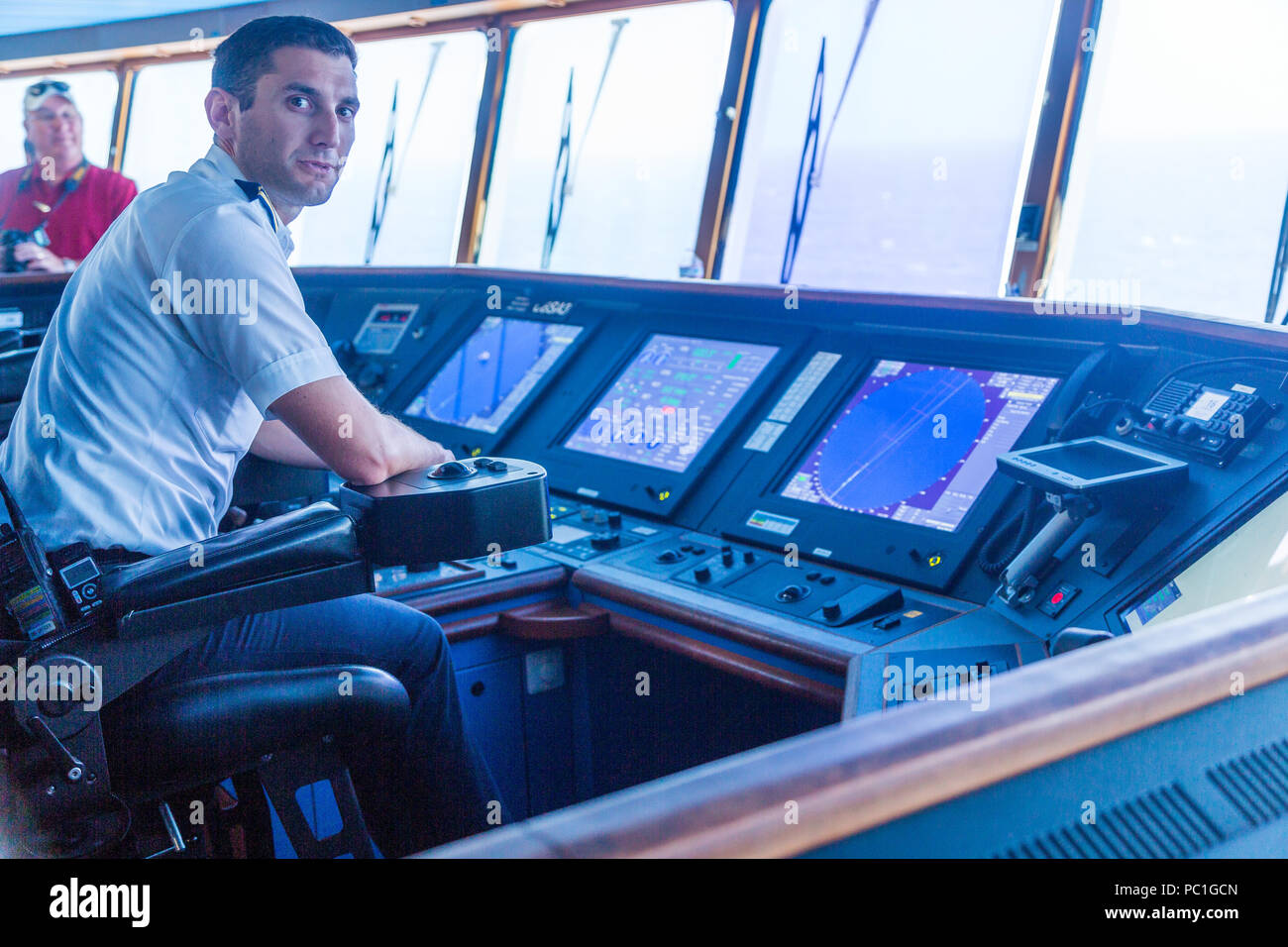 Ein Schiffsoffizier in's Captain Stuhl eines Kreuzfahrtschiffes Brücke Stockfoto