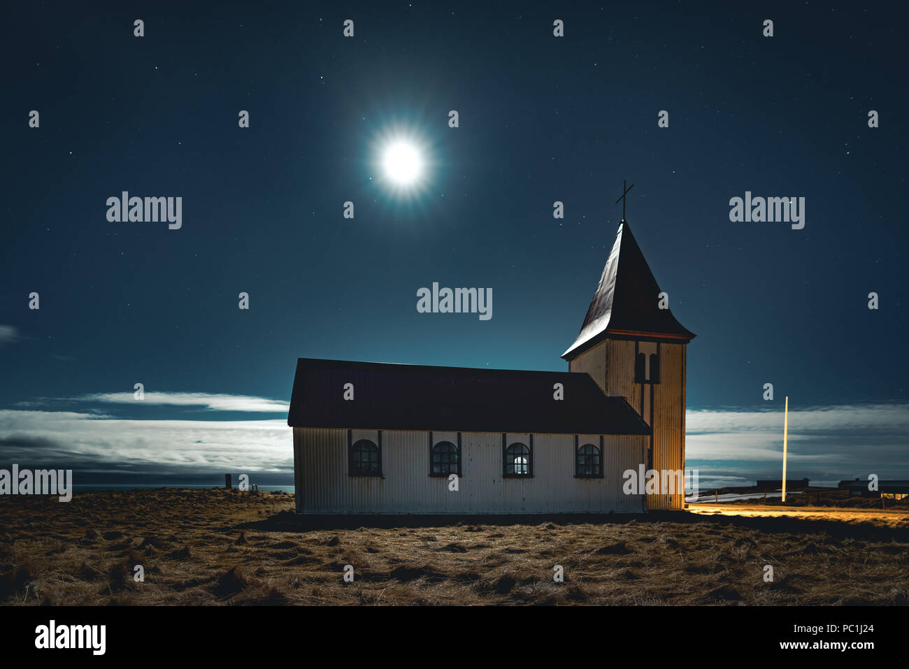 Kleine Kirche in Island Snaefellsnes bei Nacht mit Mond Sterne blau Himmel und Wolken. Stockfoto