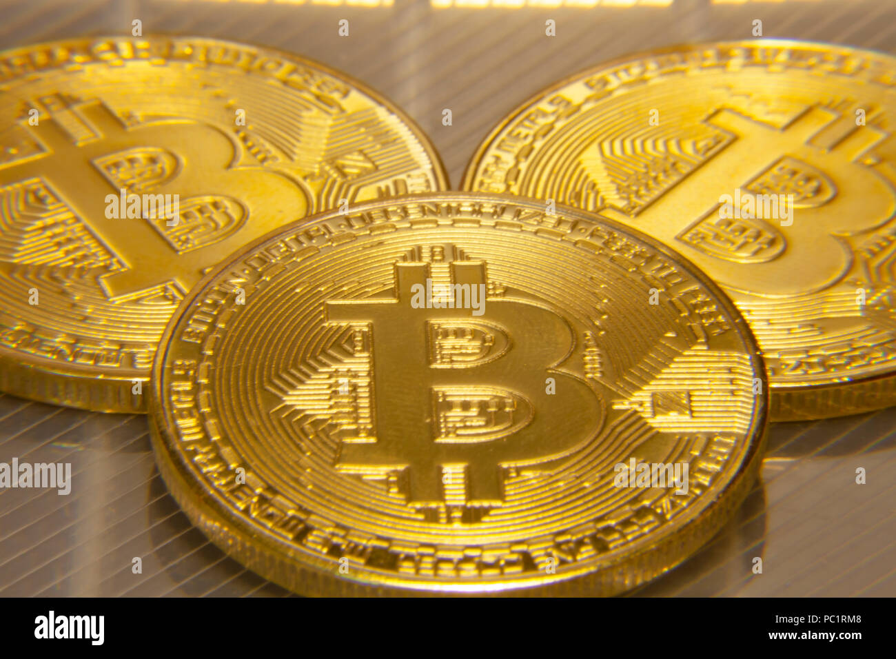 Makro Nahaufnahme: drei physischen golden Bitcoins (digitale virtuelle crypto-Währung) auf einer semi-transparente Oberfläche. Stockfoto