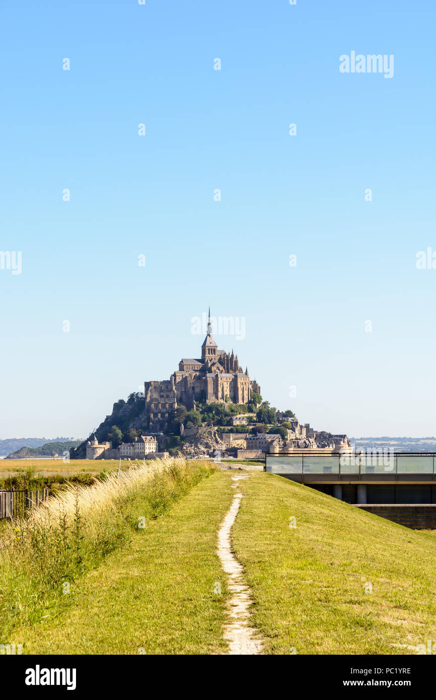 Blick auf den Mont Saint-Michel tidal Island in der Normandie, Frankreich, mit einem Weg entlang des Couesnon Fluss in Richtung der Insel im Vordergrund. Stockfoto