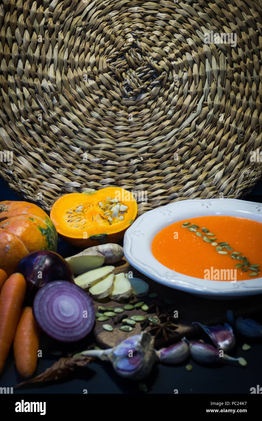 Kürbissuppe und Kürbis mit Herbst Gemüse (Knoblauch, Karotten, Zwiebeln, Gewürze, Samen). Herbstliche Stimmung. Stockfoto