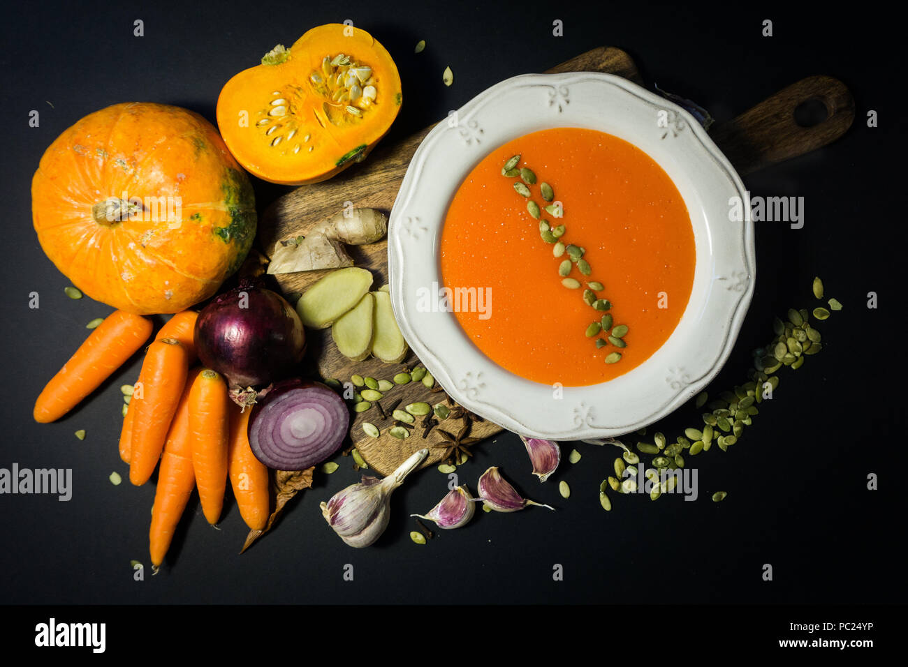 Kürbissuppe und Kürbis mit Herbst Gemüse (Knoblauch, Karotten, Zwiebeln, Gewürze, Samen). Herbstliche Stimmung. Stockfoto