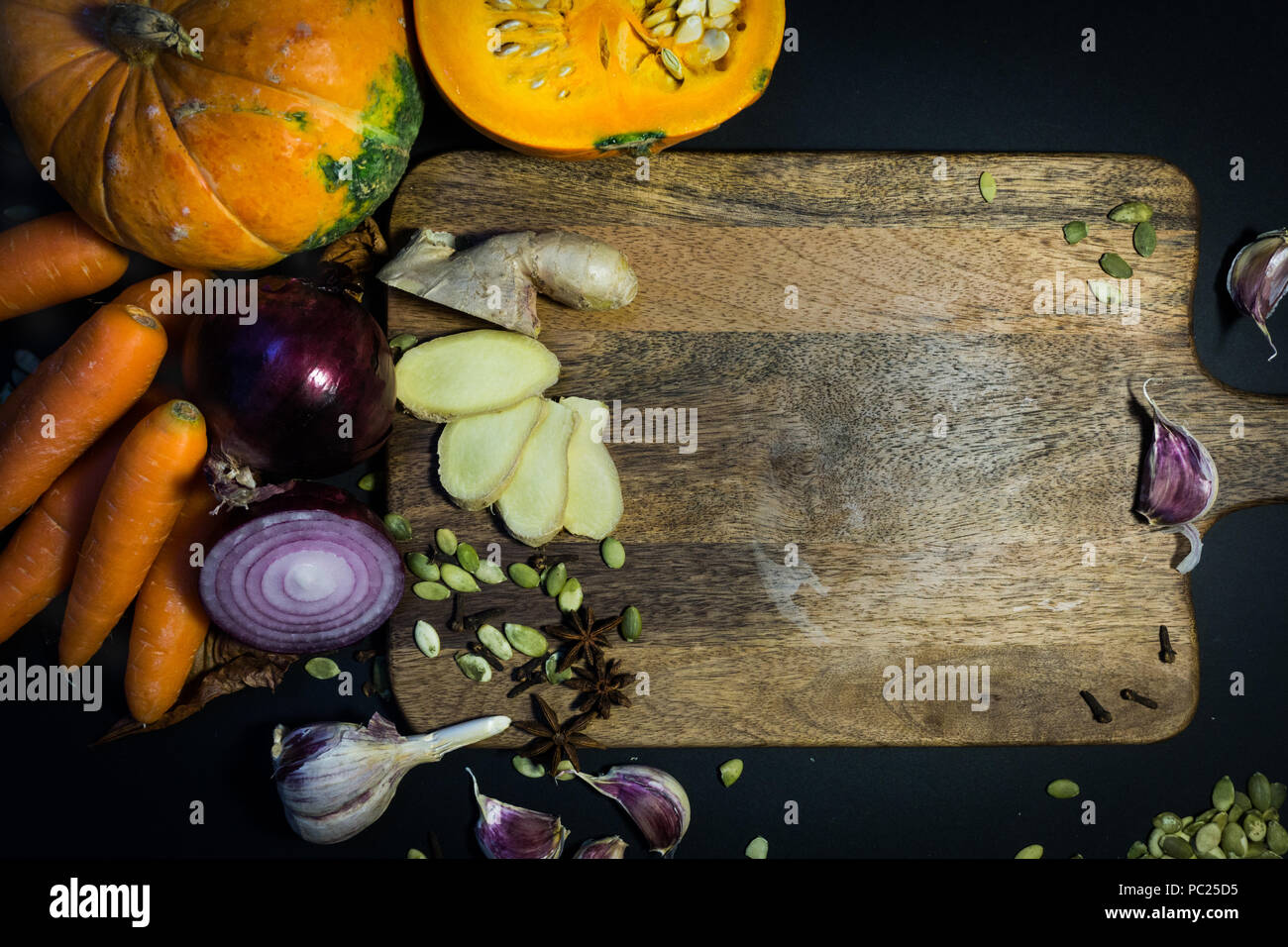Kürbis und Herbst Gemüse (Karotten, Ingwer, Knoblauch, Zwiebeln) auf dem Holzbrett. Herbstliche Stimmung. Stockfoto