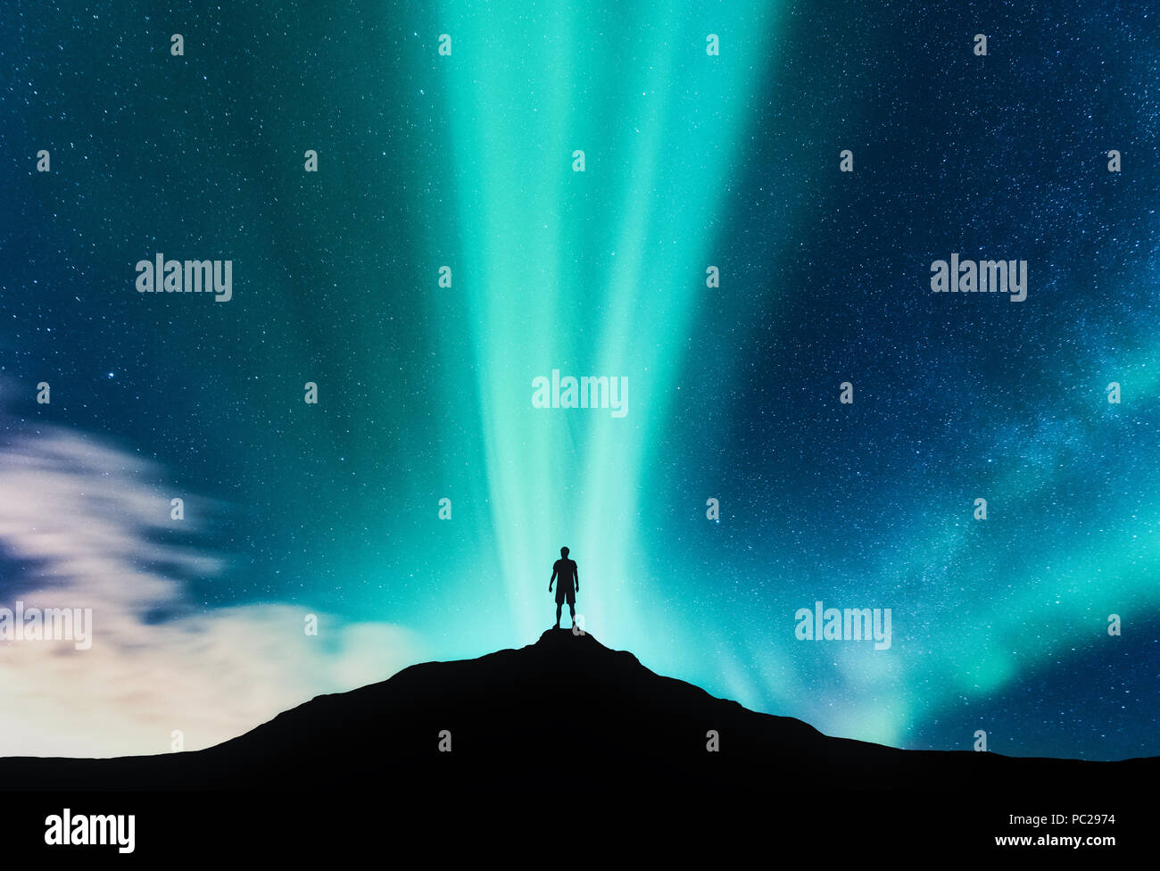 Aurora borealis und Silhouette der stehende Mann auf dem Berg. Aurora und Reisenden. Sternenhimmel und grüne Polarlichter. Nacht Landschaft mit nördlichen Stockfoto