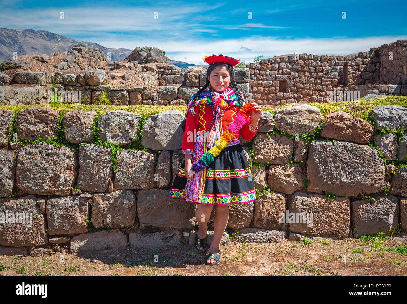 Jungen indigenen Quechua Dame in traditioneller Kleidung und Frisur in der Inka Ruine von tipon in der Nähe der Stadt Cusco. Stockfoto