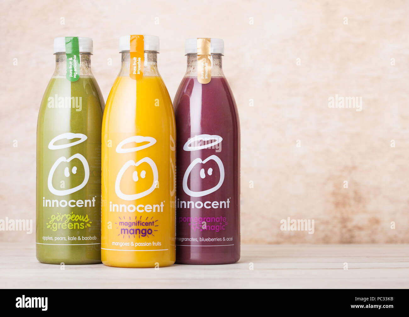 LONDON, Großbritannien - 10 August 2018: Flaschen von Unschuldigen Bio smoothie Fruchtsaft Getränk mit Mango und Birne und Heidelbeeren Geschmack auf Holz. Stockfoto