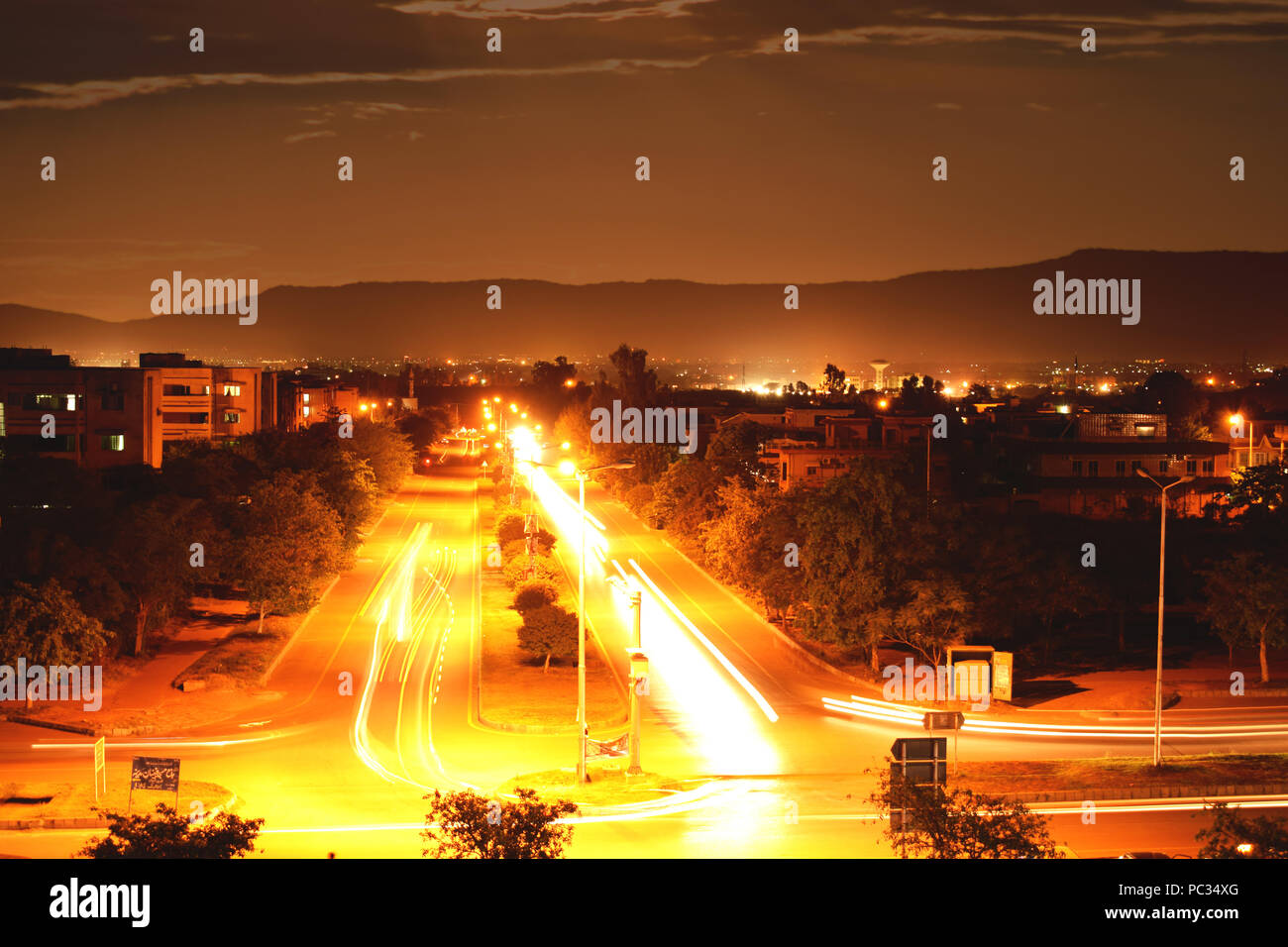 Leichte Wanderwege Fotografie in der Stadt. Lichter der Autos mit bewölktem Himmel und die Berge im Hintergrund. Lange Belichtung & Verschlusszeit erfasst Stockfoto