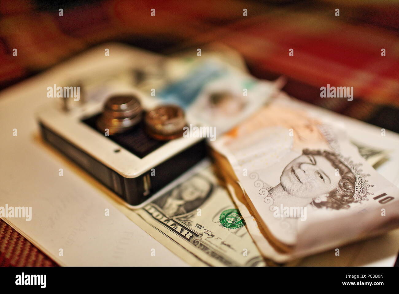 Energie und Geld Konzept Foto mit Akku, Dollar und Pfund Sterling lautende Banknoten und Münzen Durcheinander im Rahmen Stockfoto