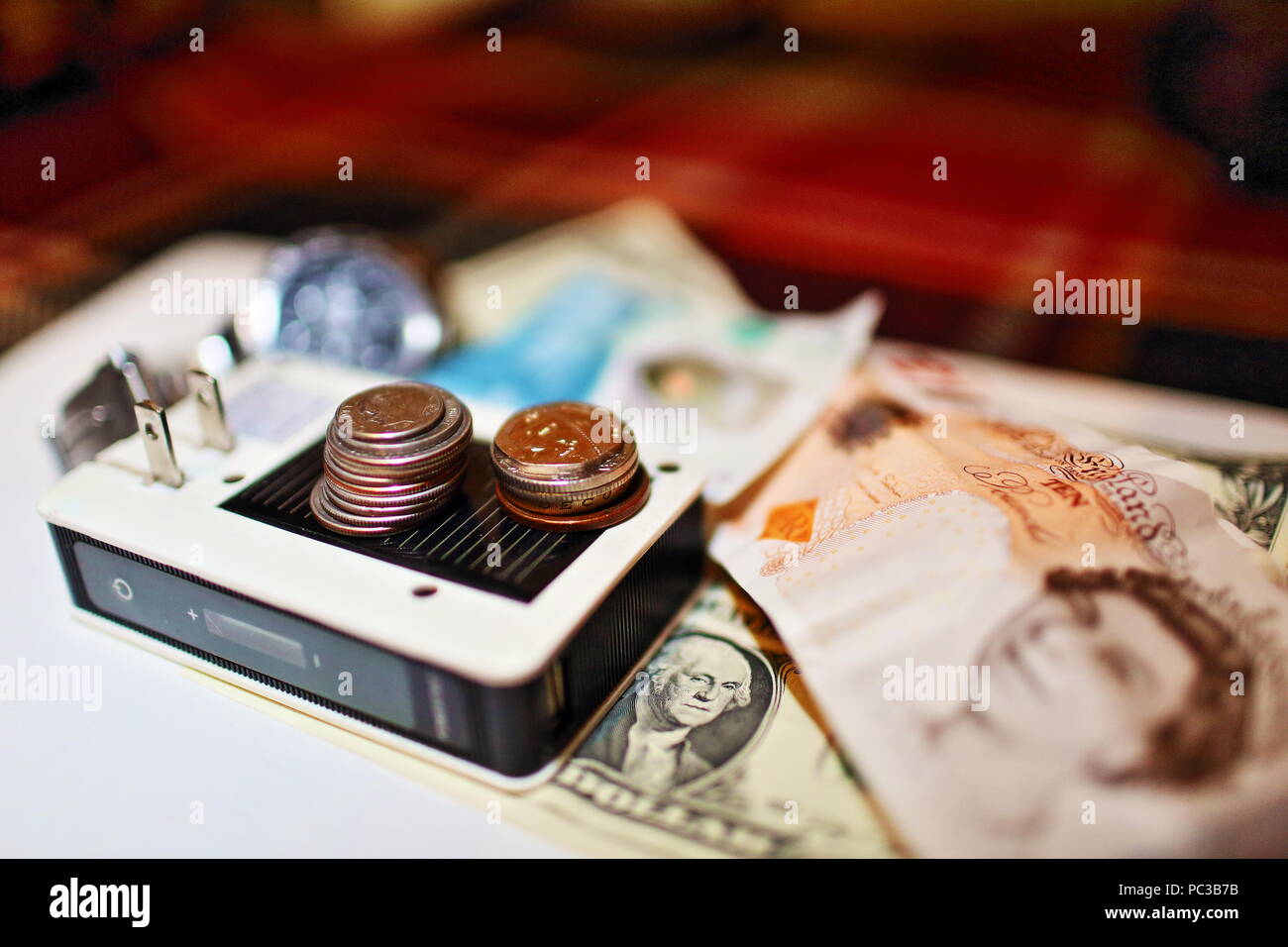 Zeit, Energie, Geld Konzept Foto mit Akku, Armbanduhr, Dollar und Pfund Sterling lautende Banknoten und Münzen Durcheinander im Rahmen Stockfoto